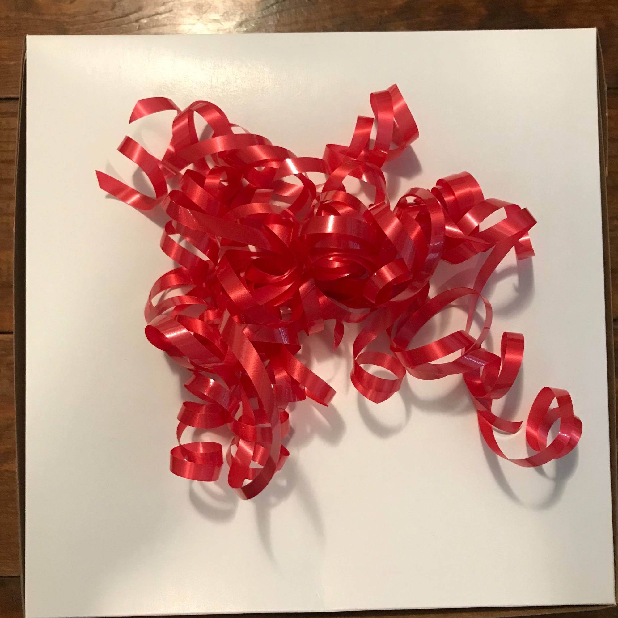 Red curly ribbon bow on a white gift box