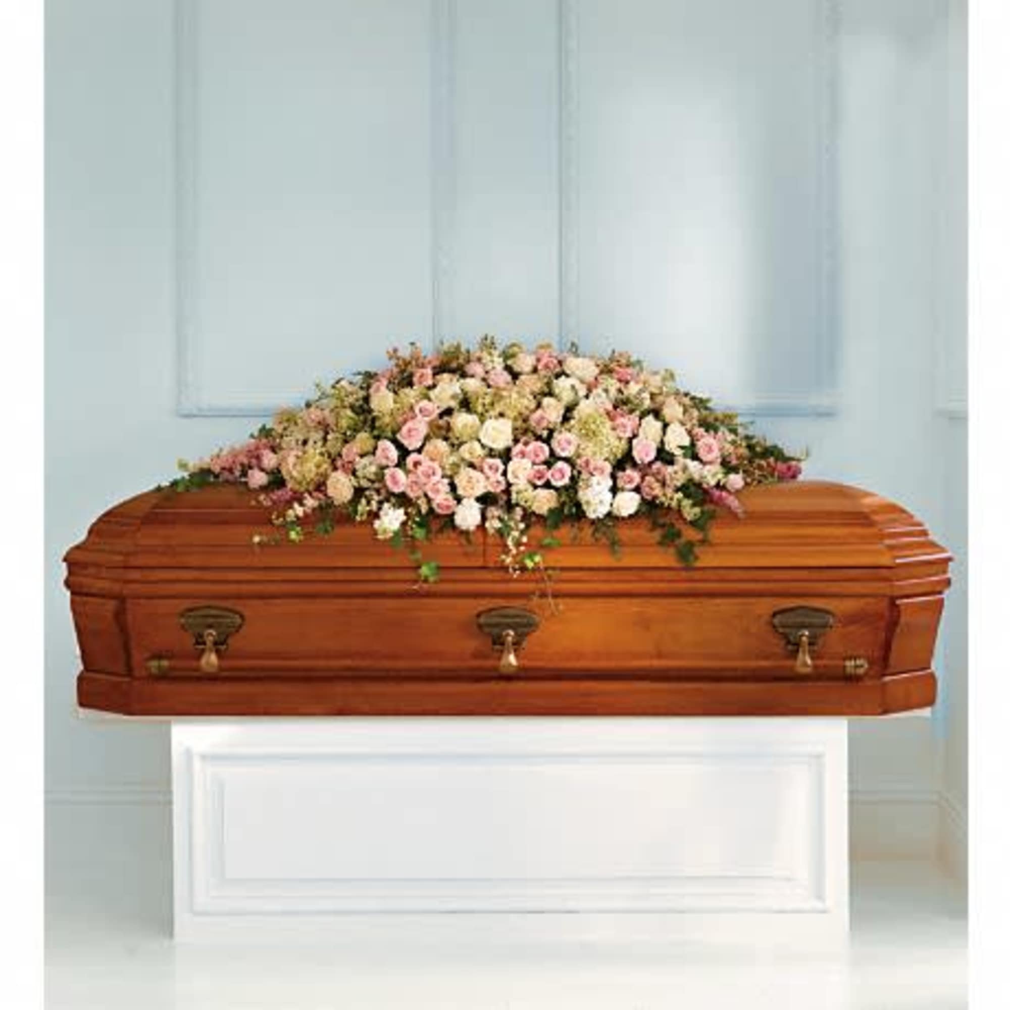 Casket topped with a pastel flower spray