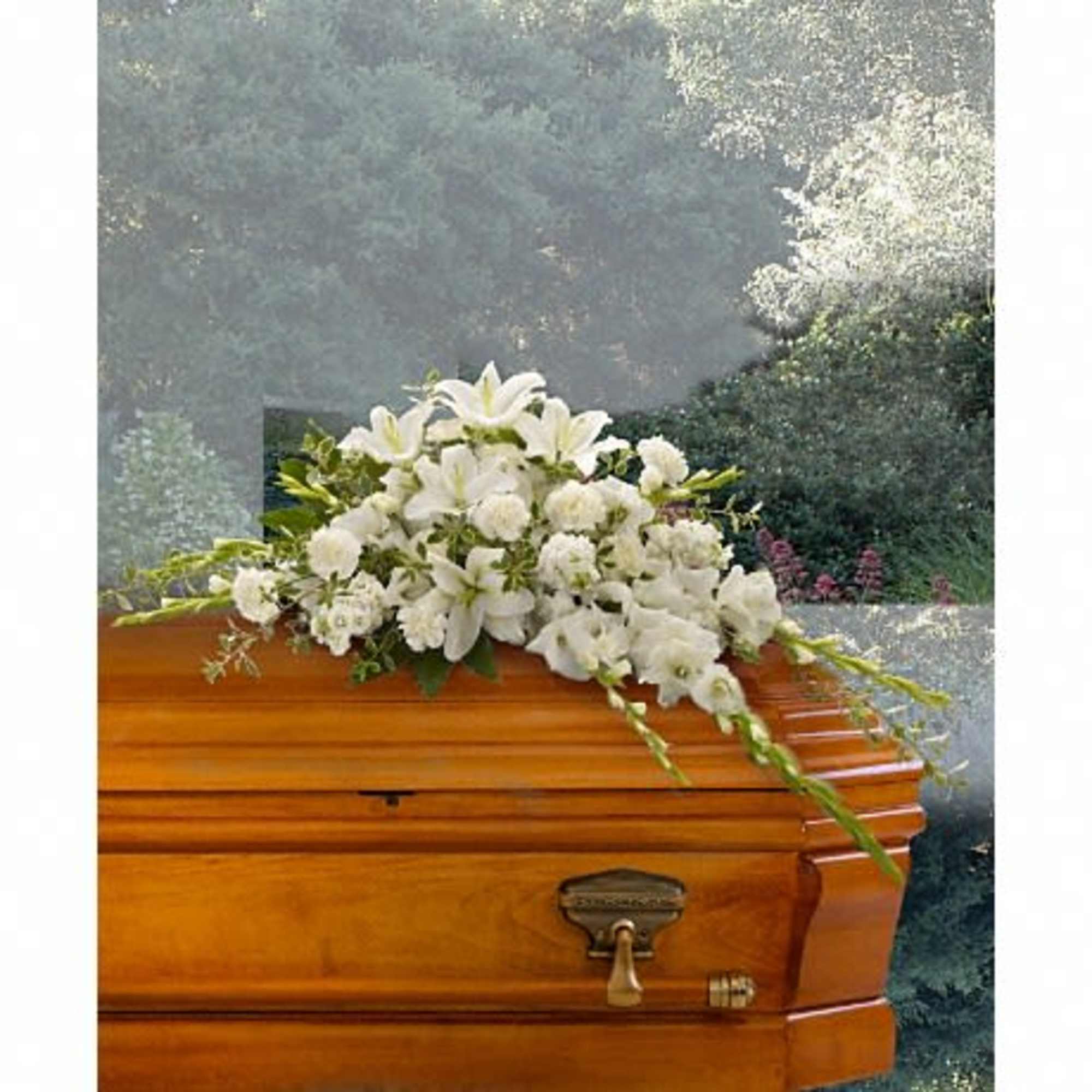 White flowers arranged on top of a wooden casket