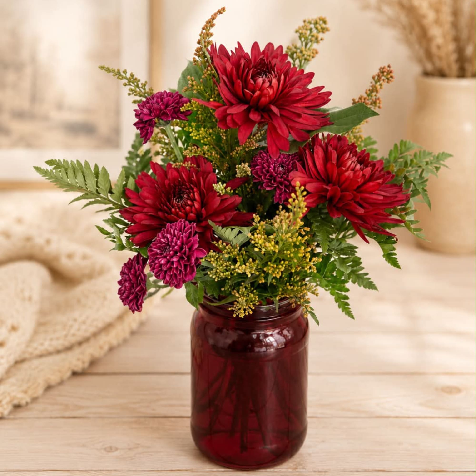 Red and purple chrysanthemum bouquet in a burgundy glass jar vase