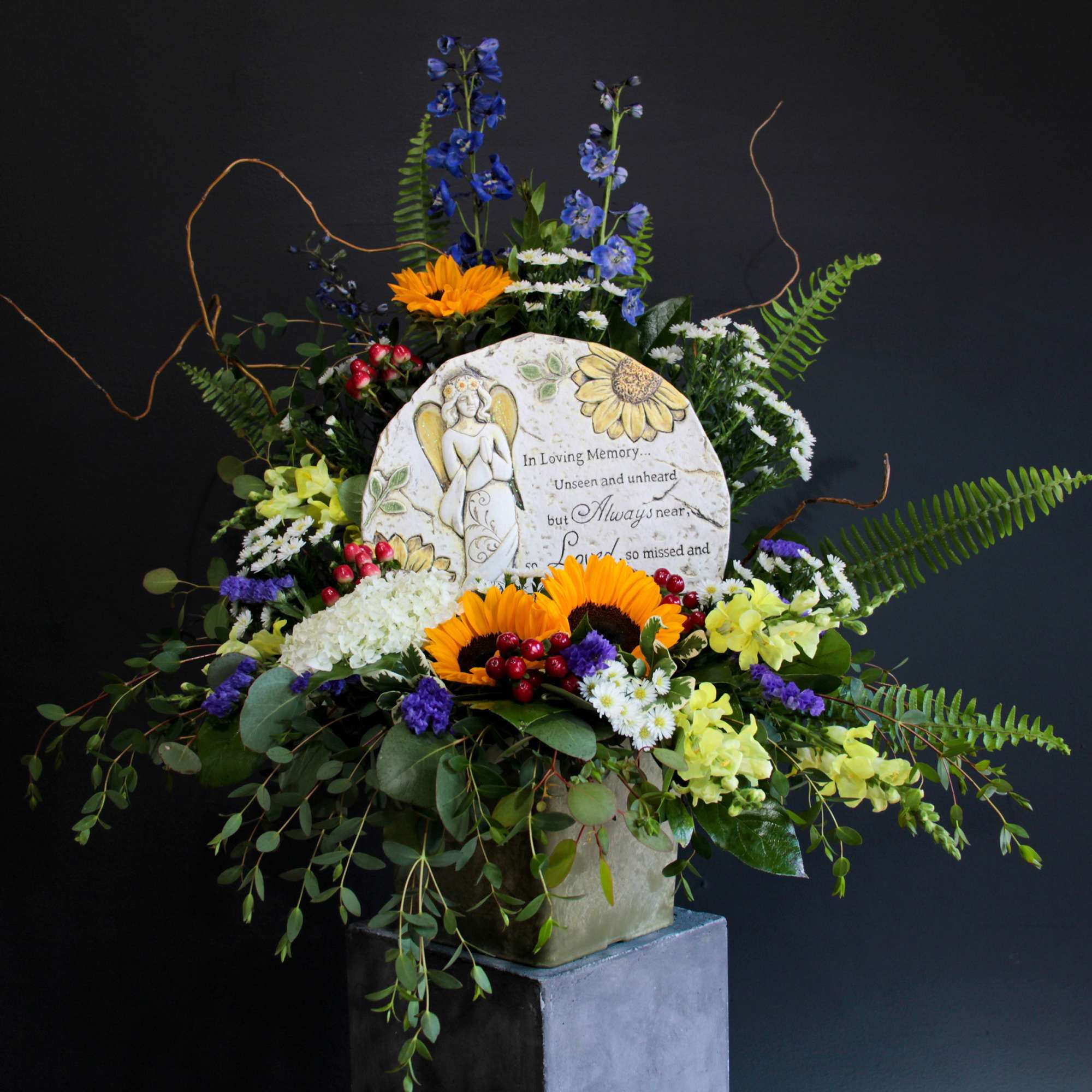 Sympathy floral arrangement with a memorial plaque and mixed flowers