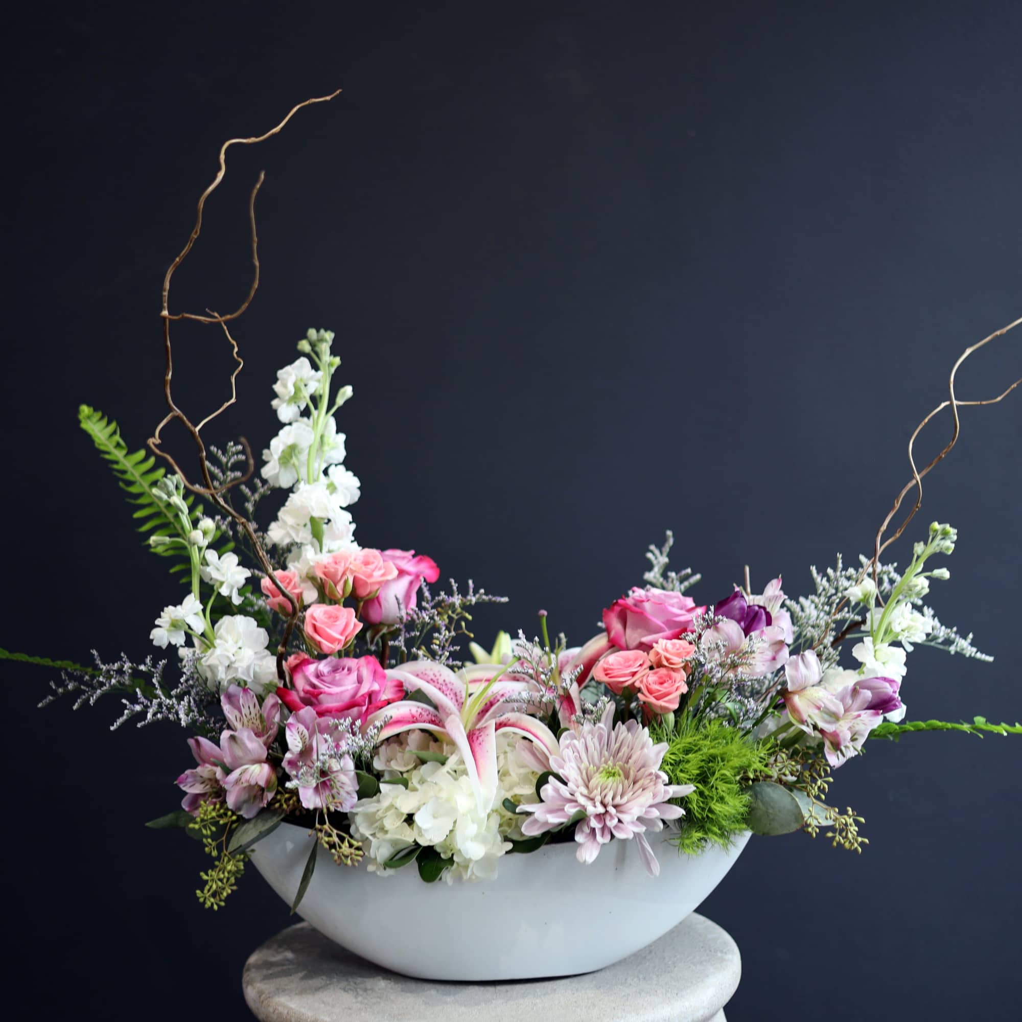 Pink and white floral arrangement in a white bowl vase
