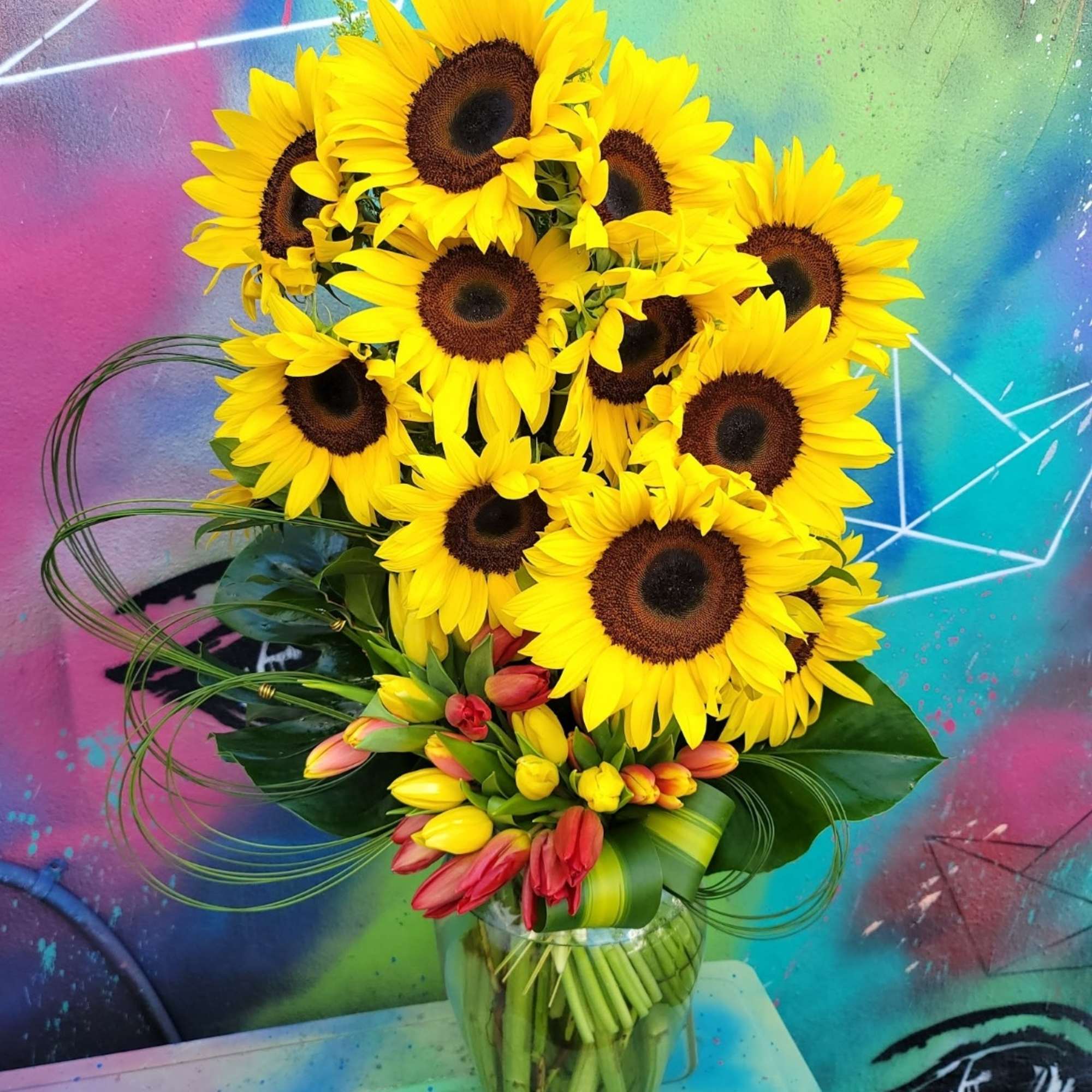 Bouquet of sunflowers and tulips in a glass vase
