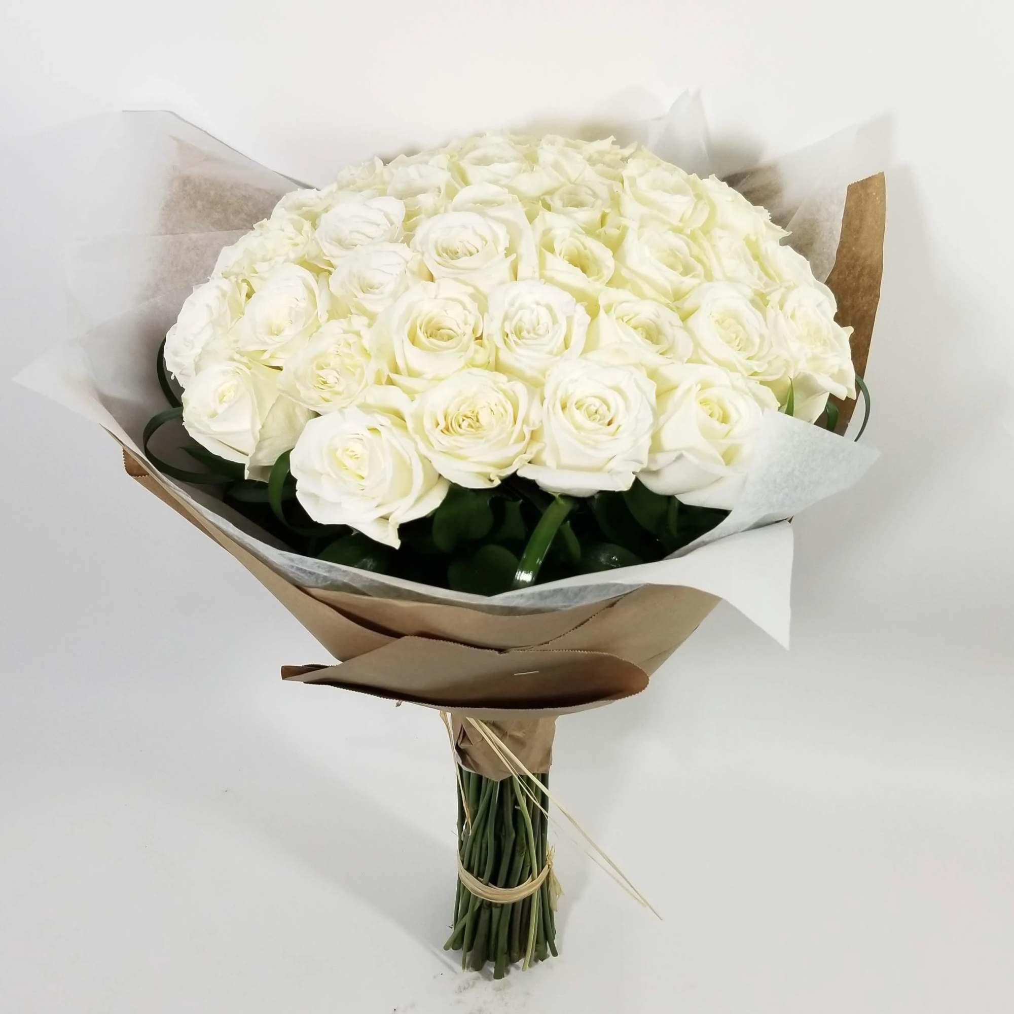 Bouquet of white roses wrapped in brown and white paper