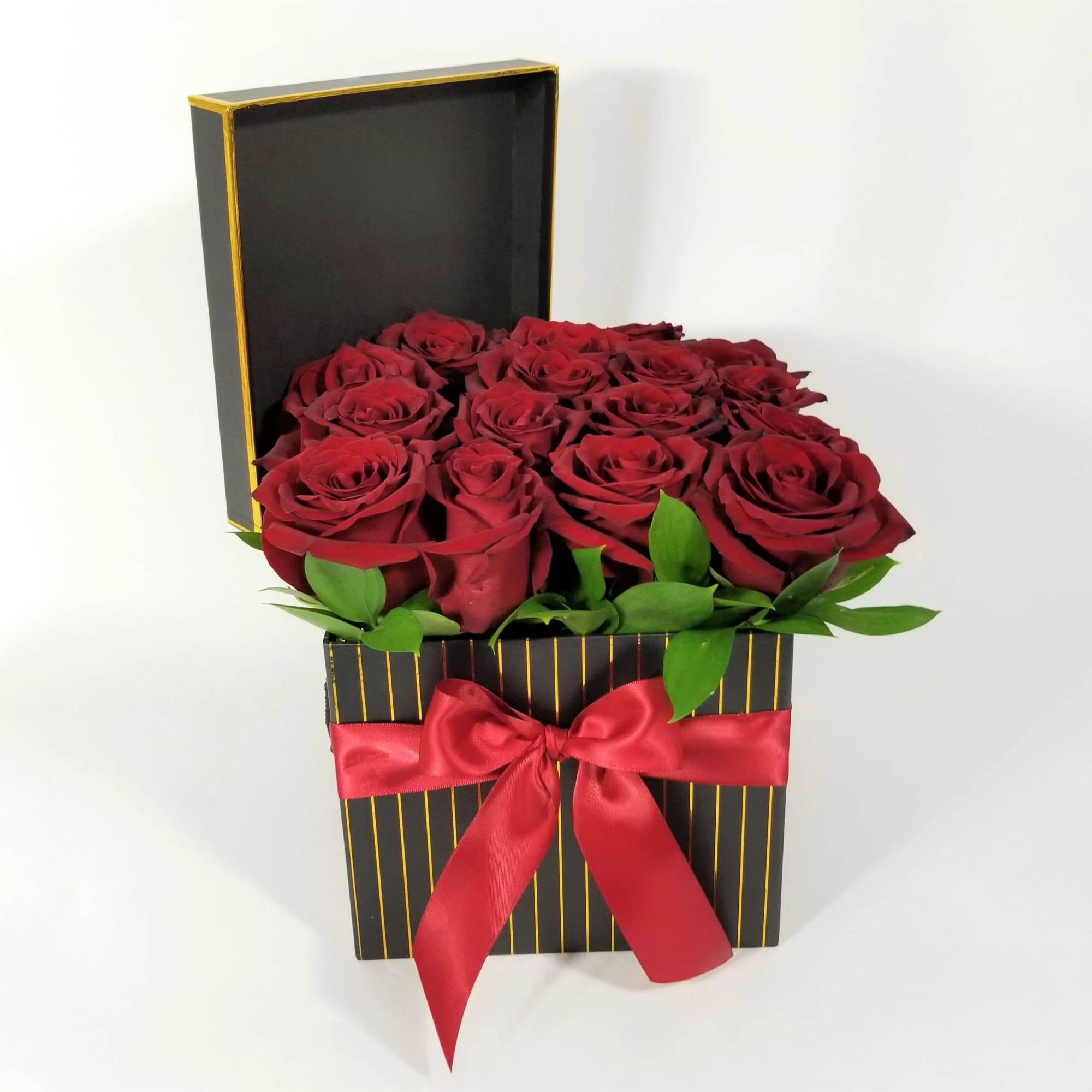 Red roses arranged in a black gift box with a red ribbon