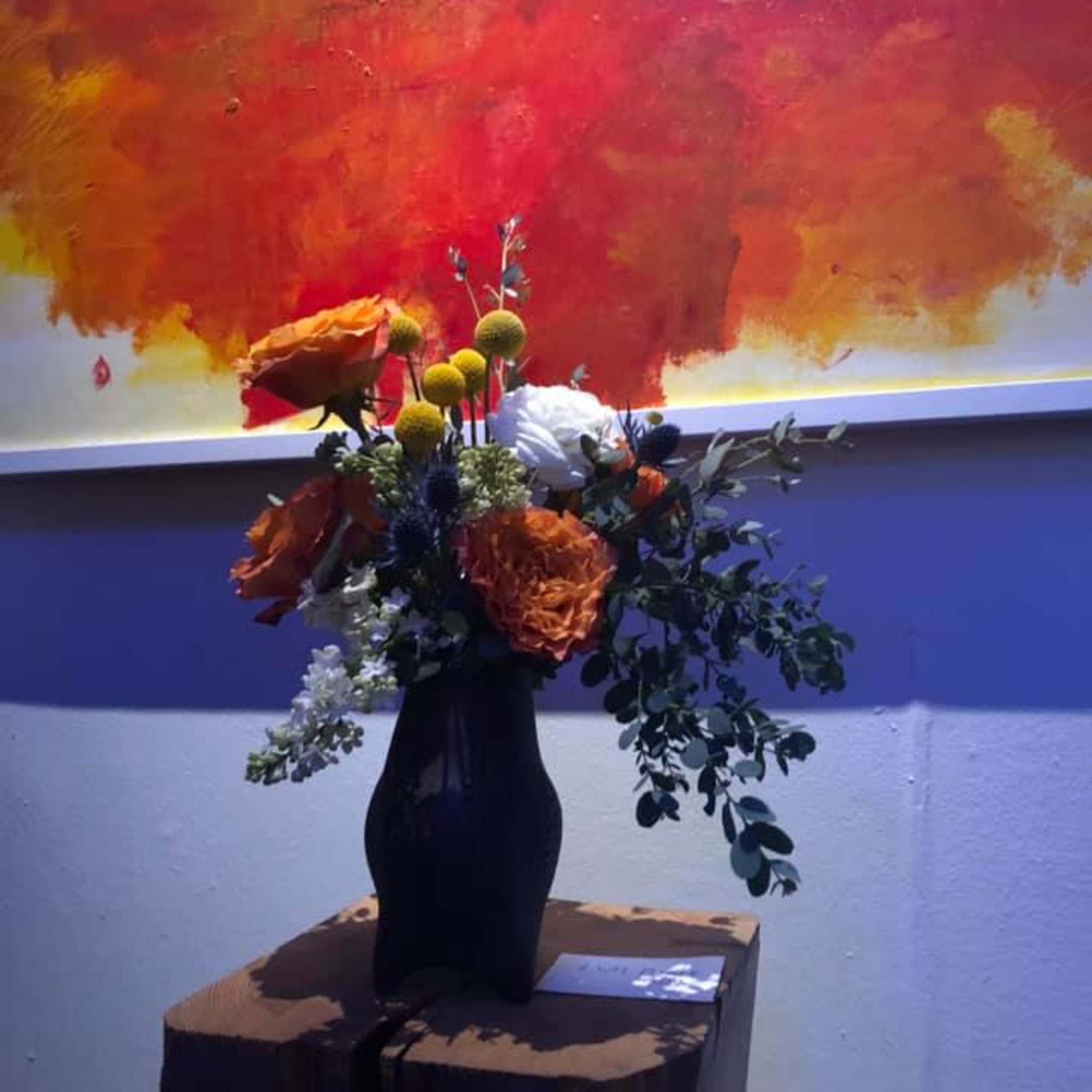 Orange and white flowers in a black vase on a pedestal