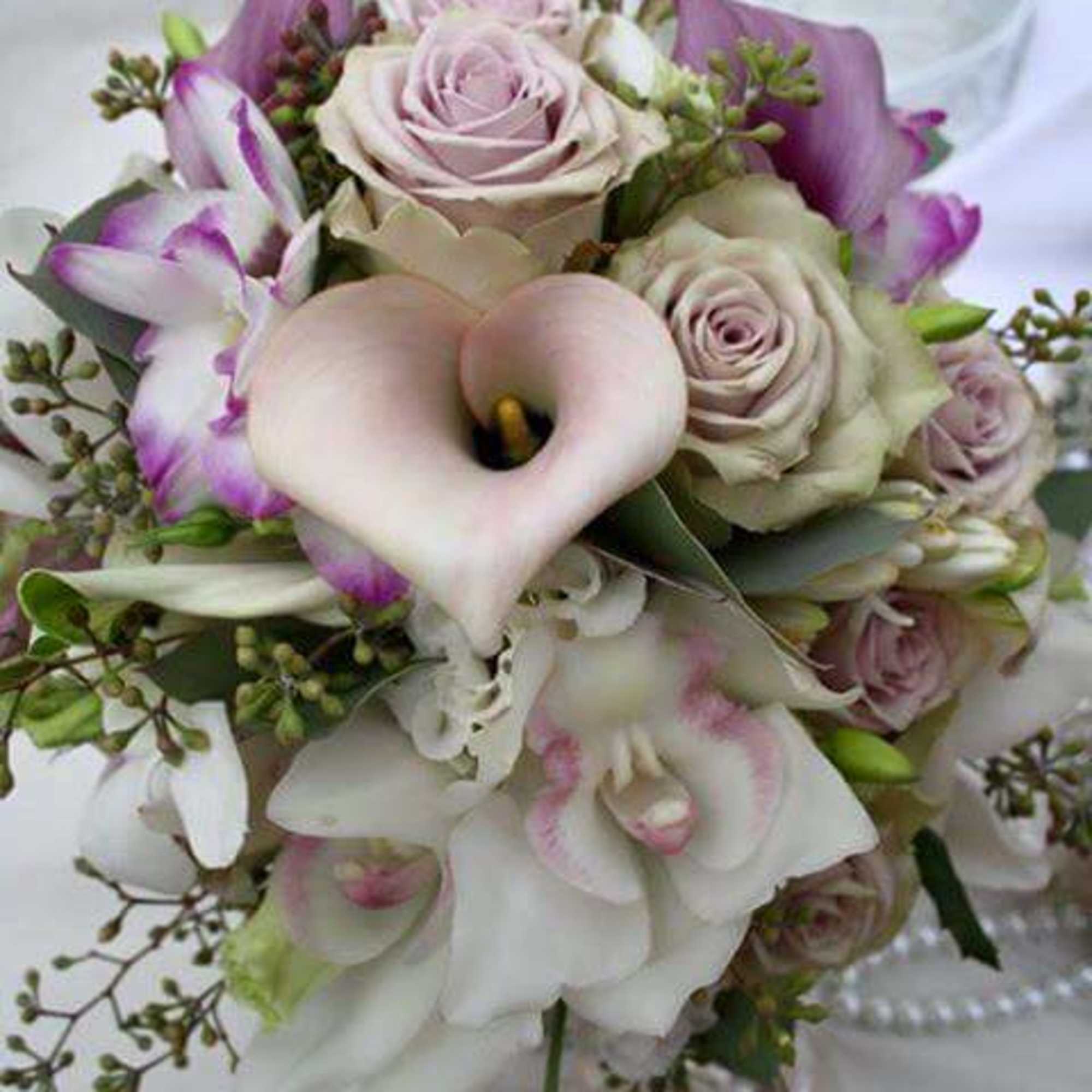 Bouquet of pale roses and white calla lilies with purple accents
