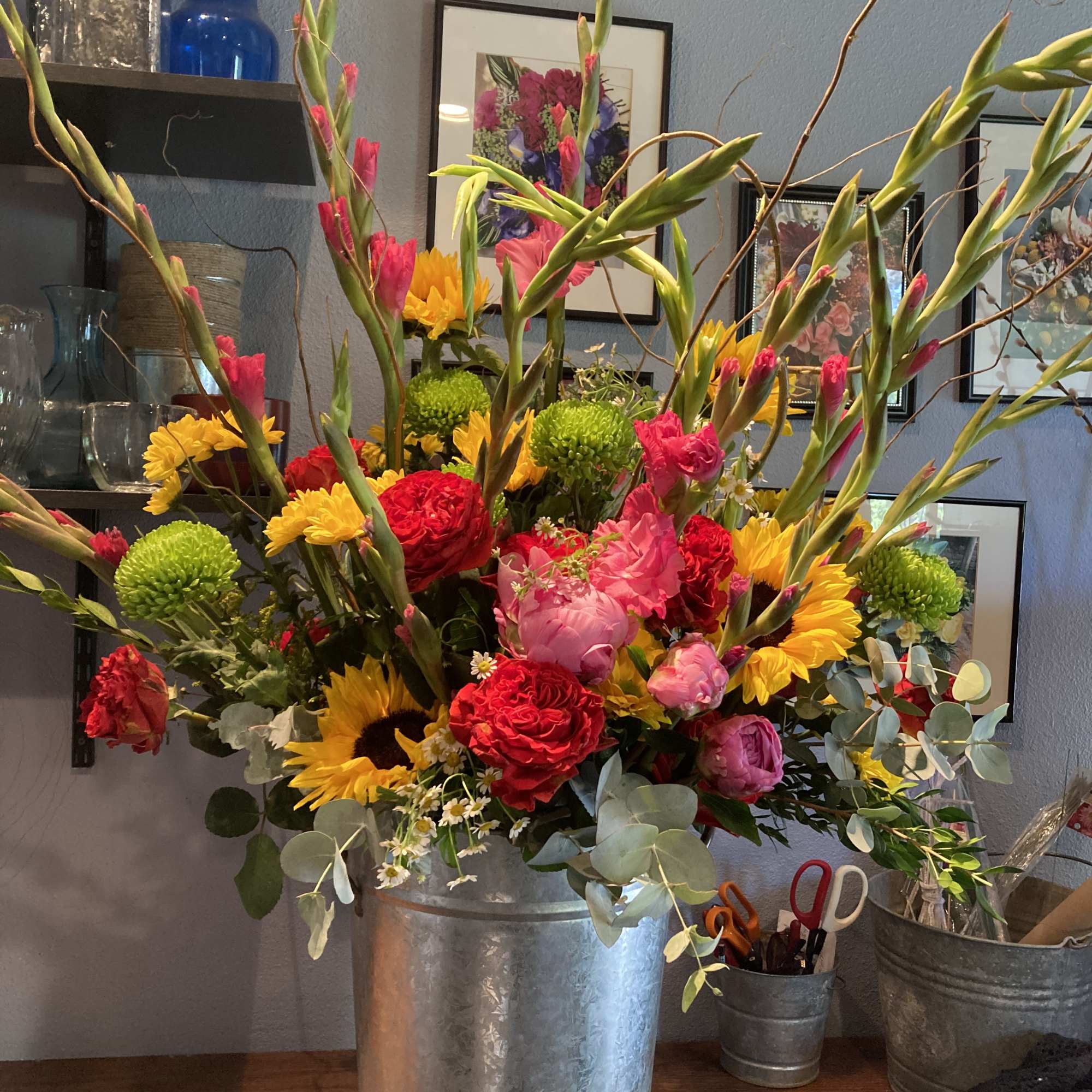 Tall mixed bouquet in a metal vase with red, pink, and yellow flowers