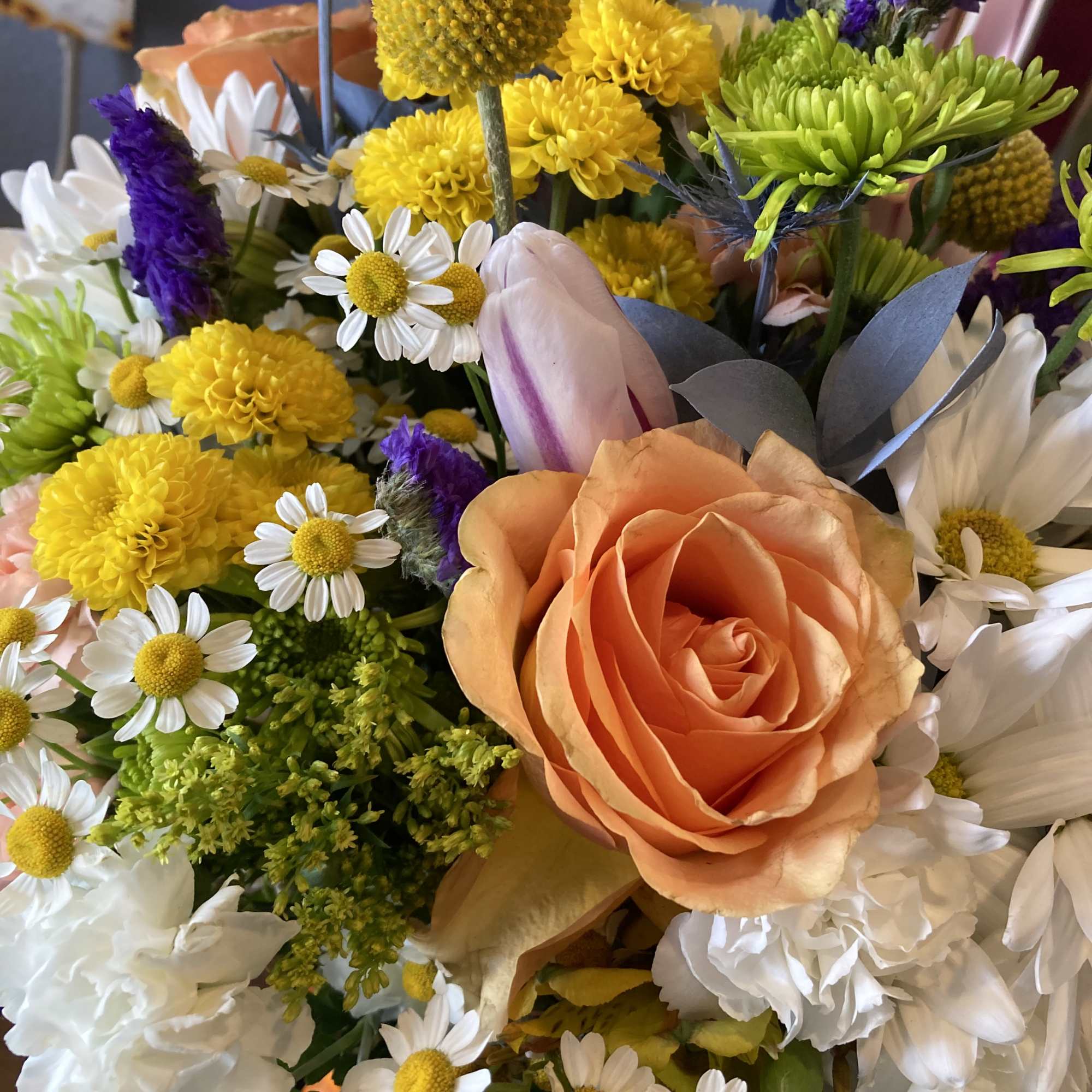 Mixed bouquet with peach roses, yellow blooms, and white daisies