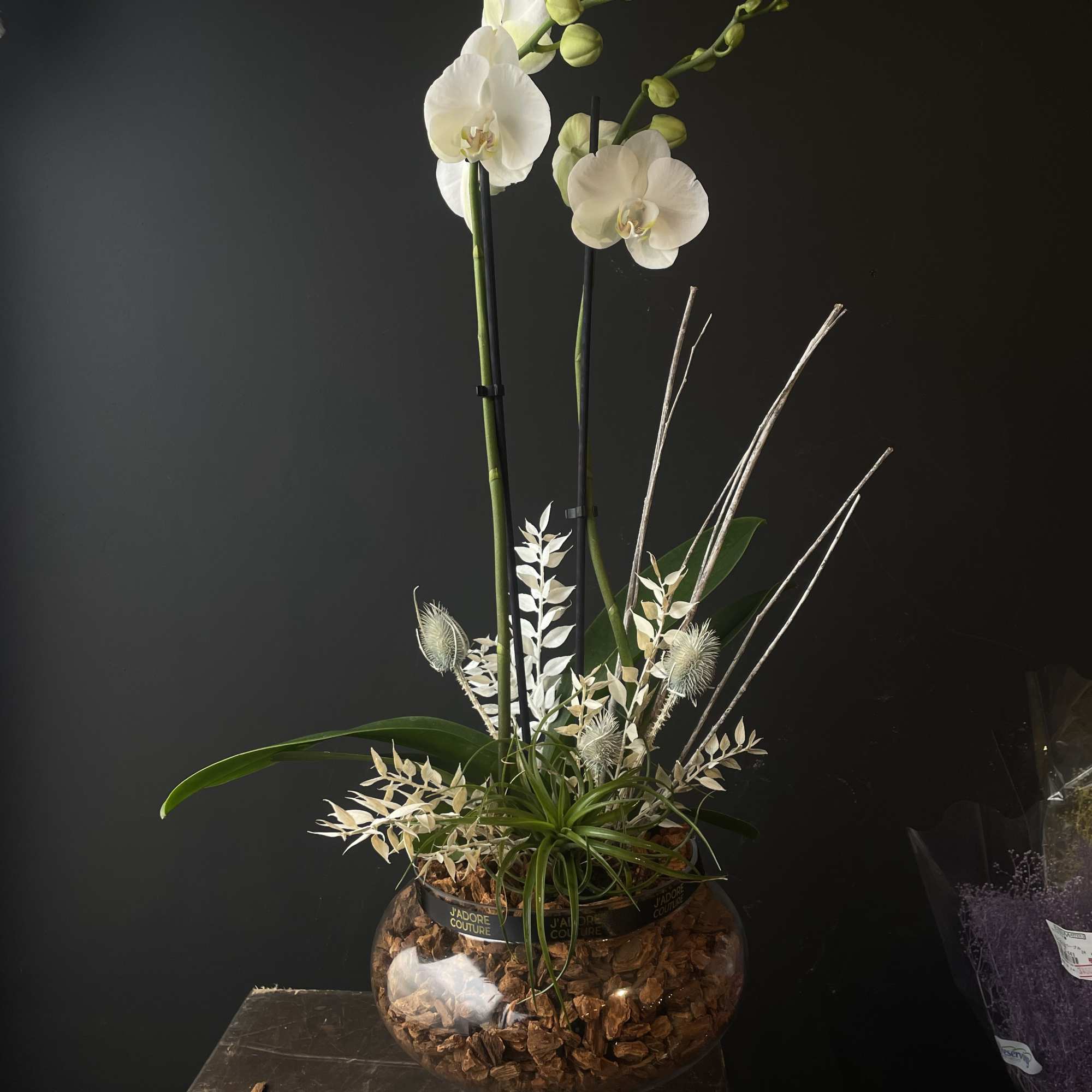 Tall white orchid arrangement in a glass bowl vase