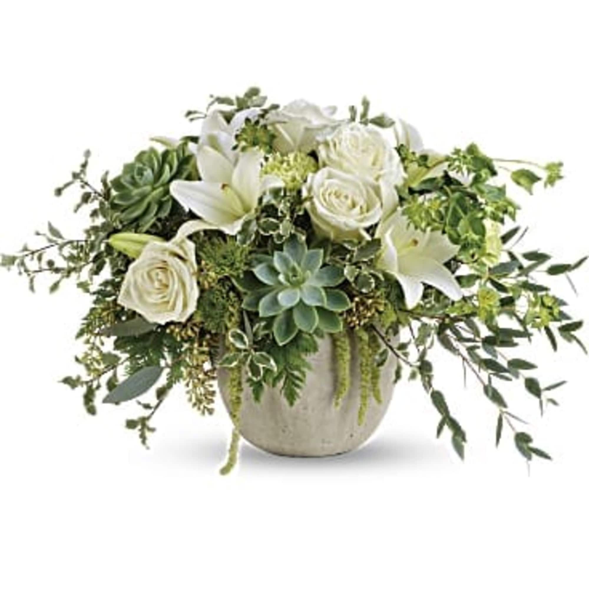 White roses and lilies in a low ceramic pot with trailing greenery