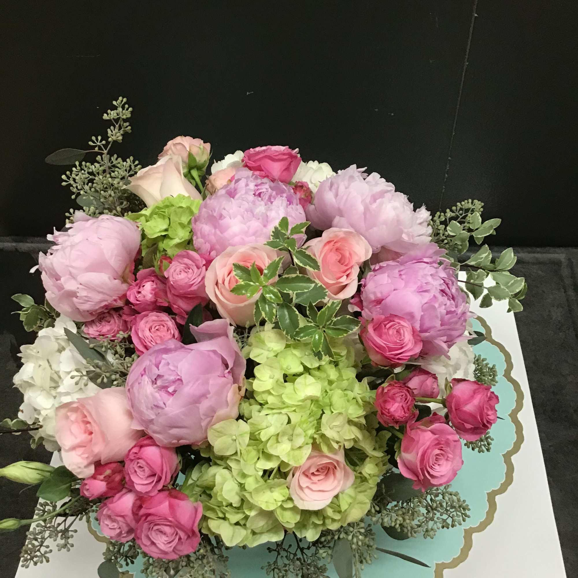 Pink and lavender bouquet with roses and peonies on a decorative box