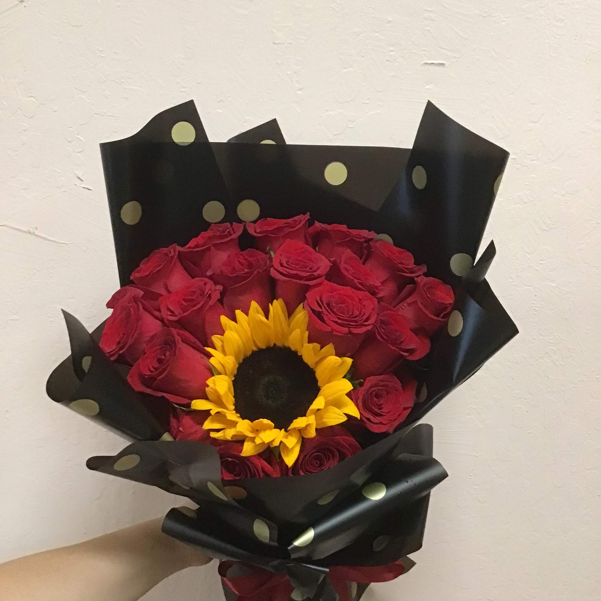Bouquet of red roses with a sunflower center wrapped in black paper