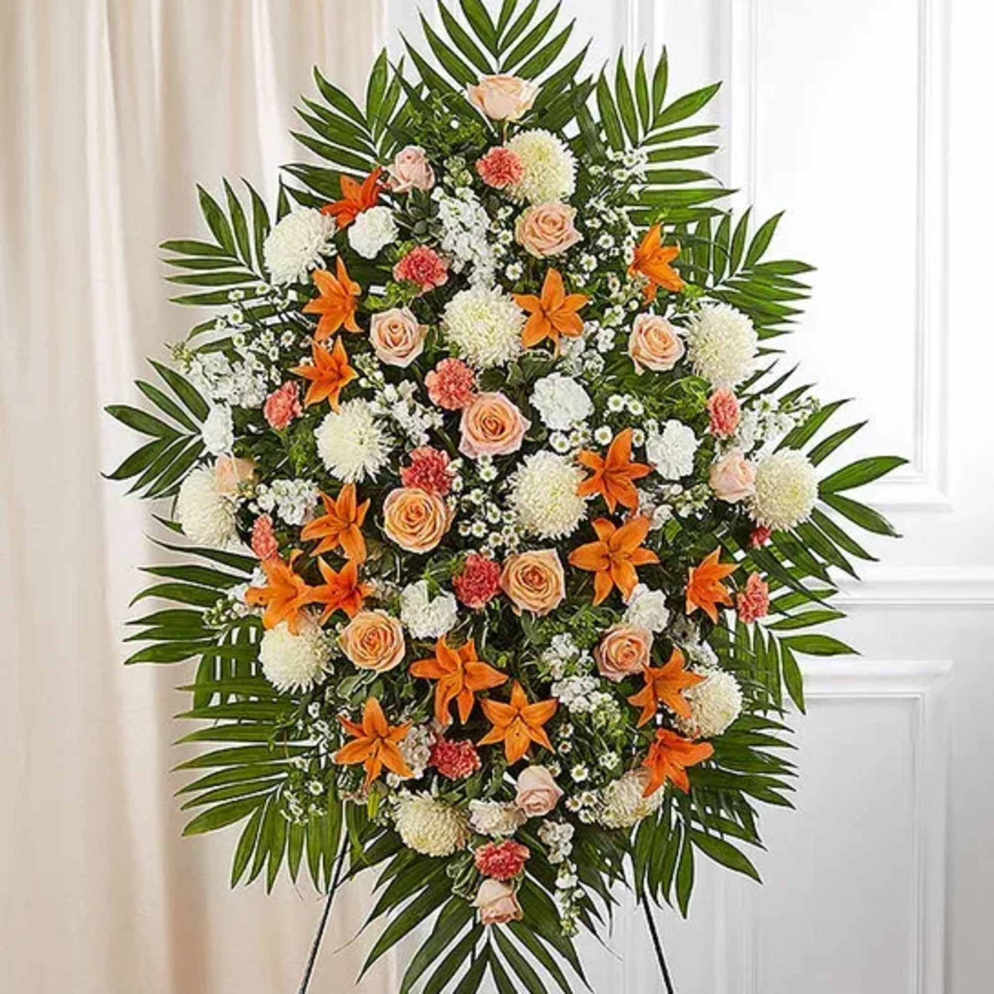 Standing floral spray with orange lilies, peach roses, and white blooms