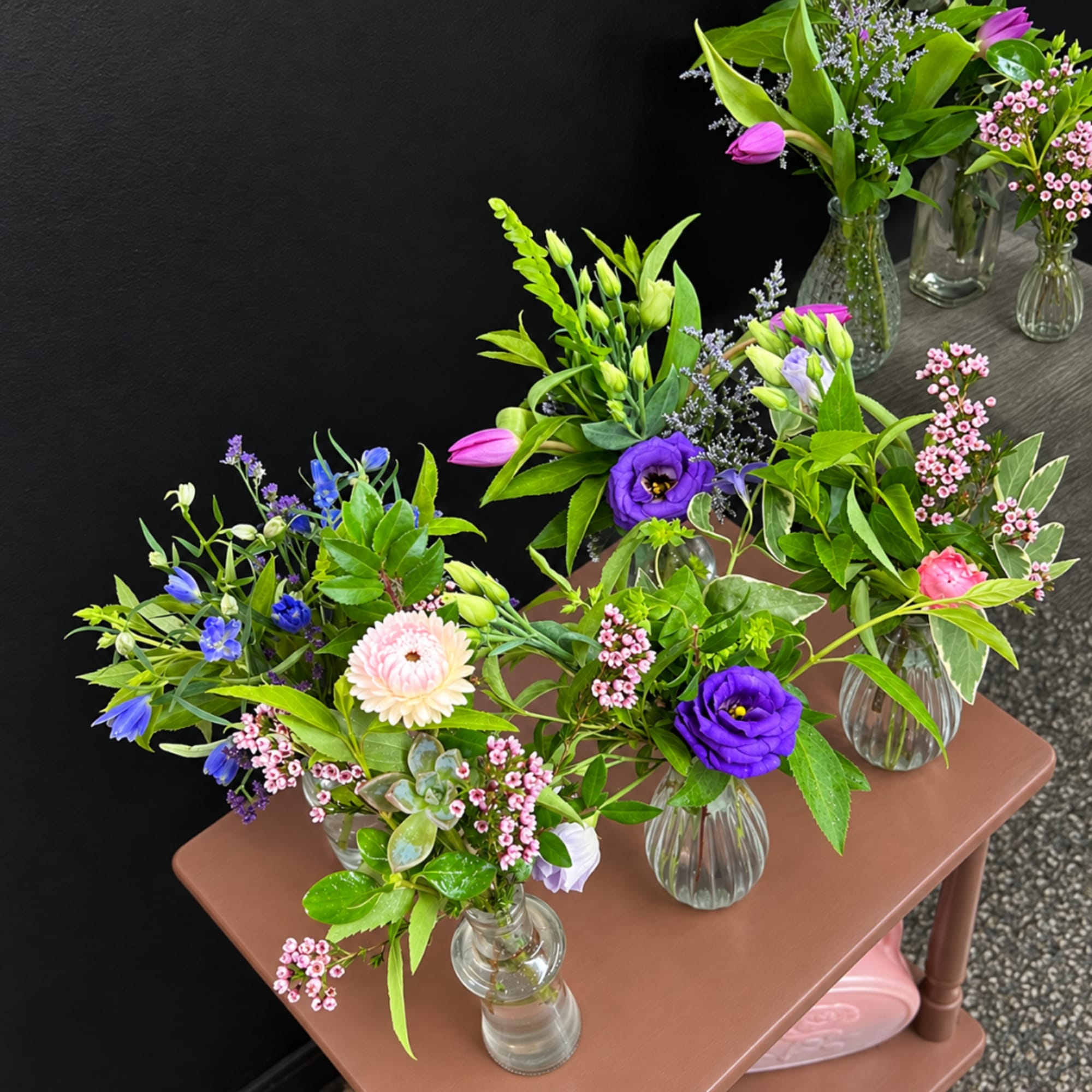 Small mixed flower arrangements in clear glass vases on a table