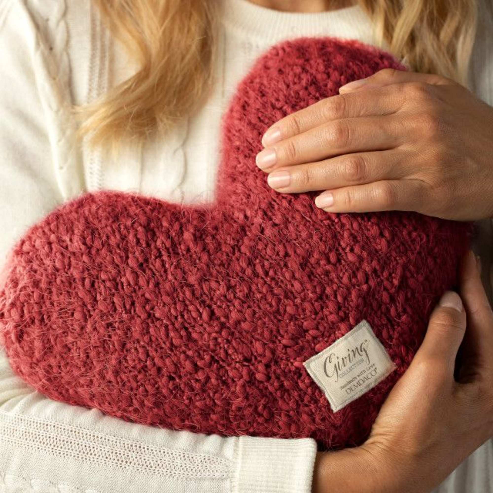 Person holding a red knitted heart pillow