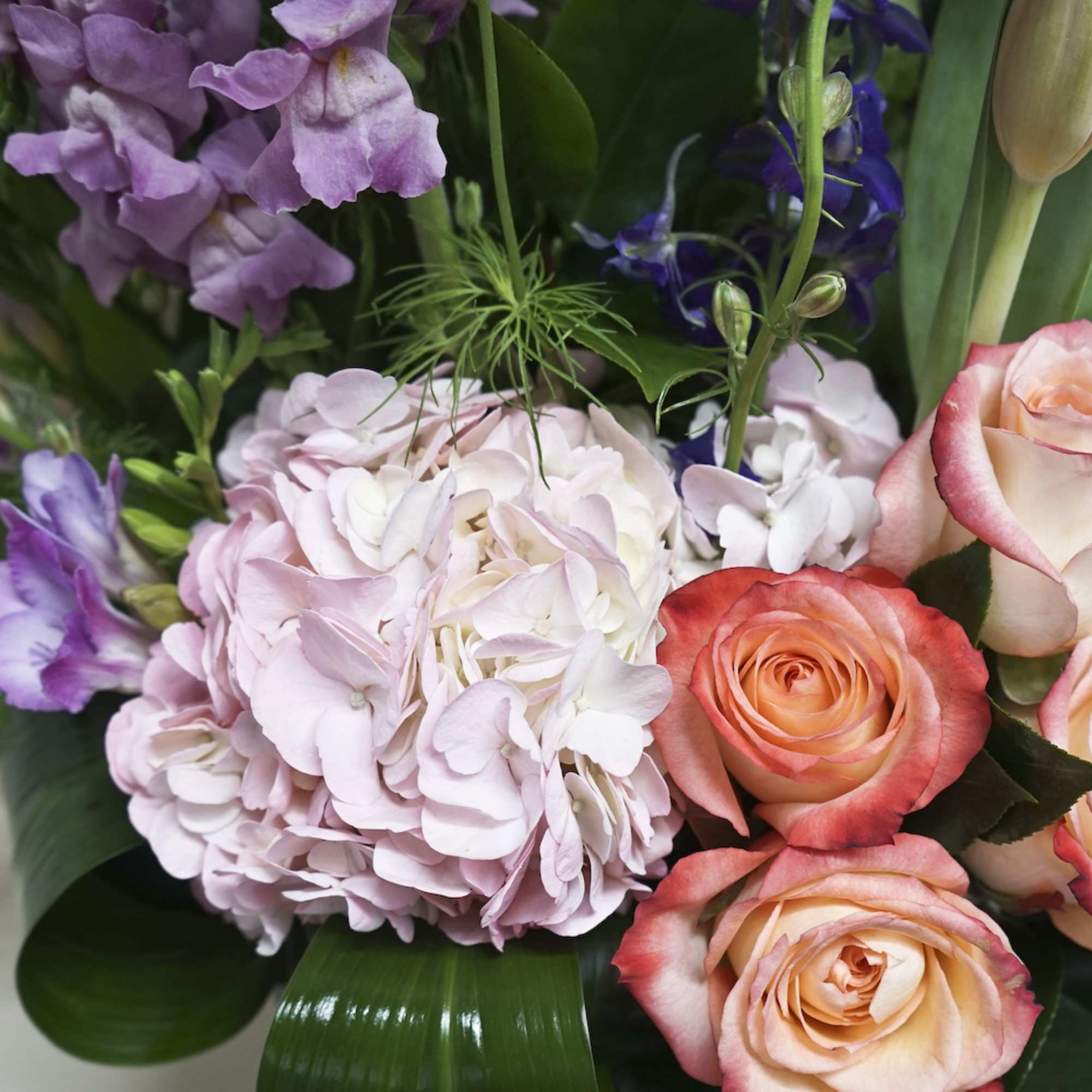 Bouquet of pink hydrangea and peach roses with purple blooms