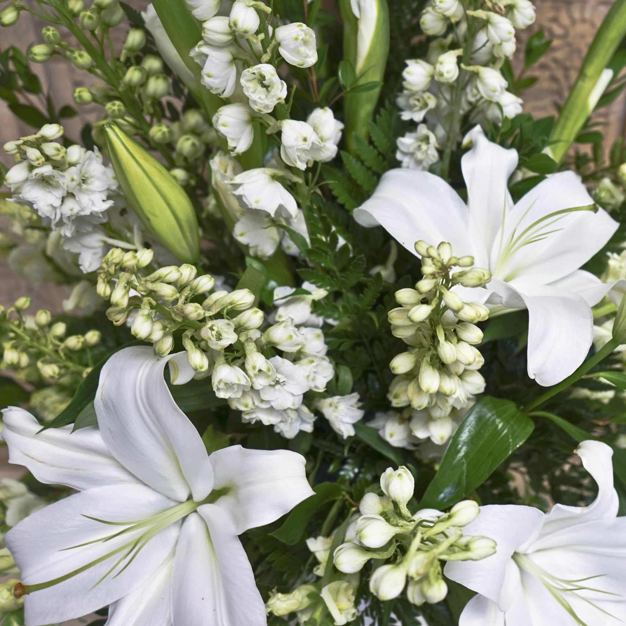White lilies and clustered white blossoms in a green bouquet