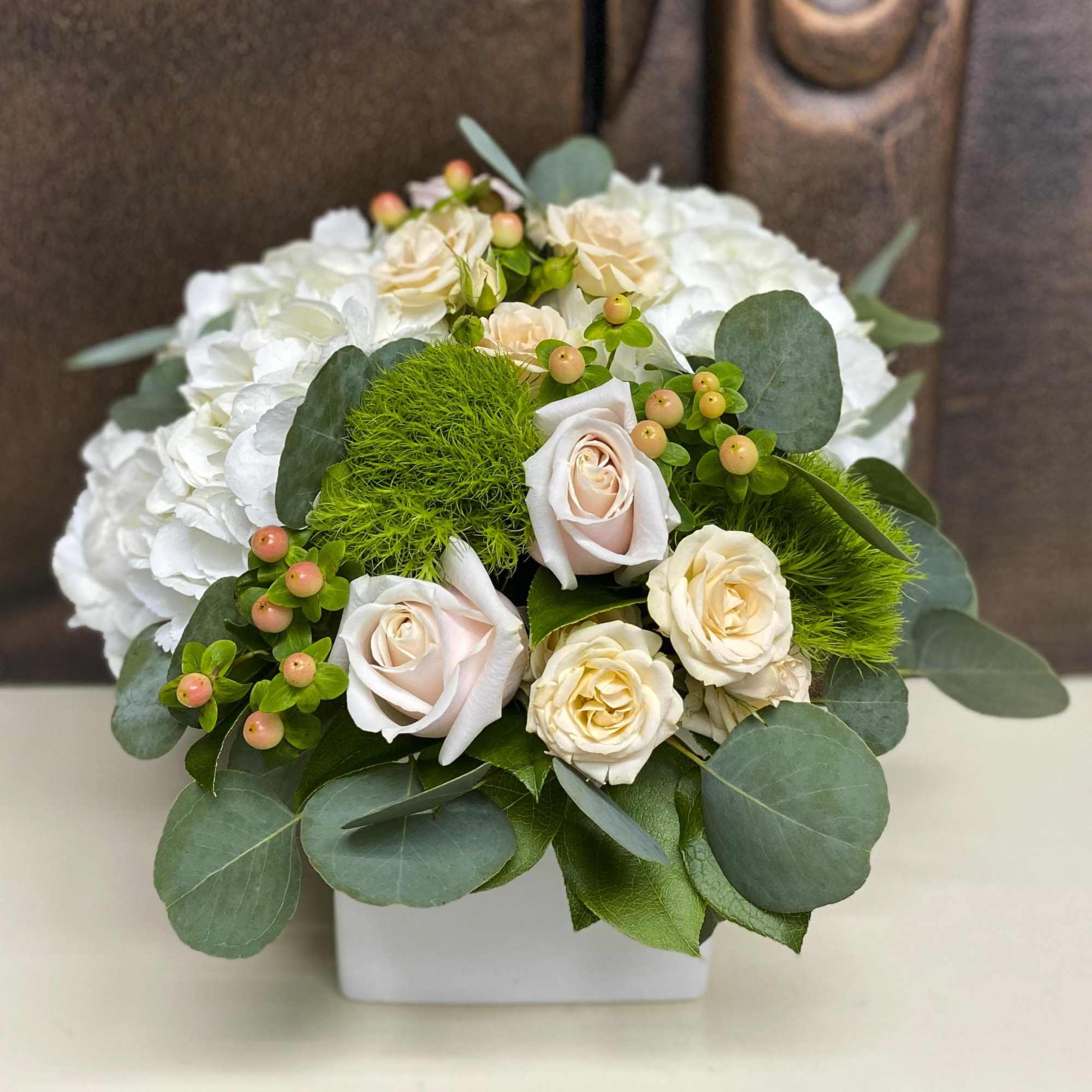 White and blush roses arranged in a square white vase