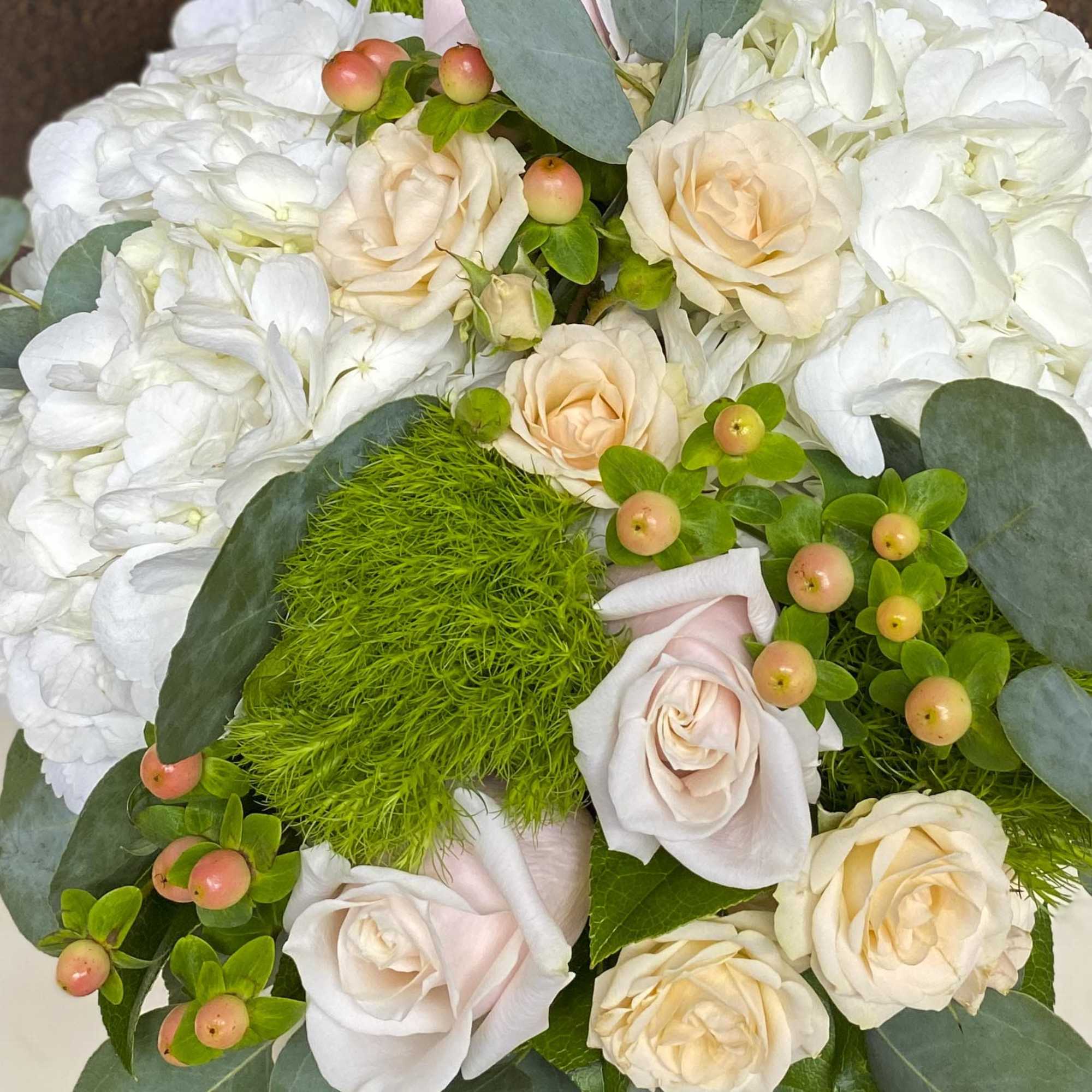 Bouquet of pale roses and white flowers with green berries