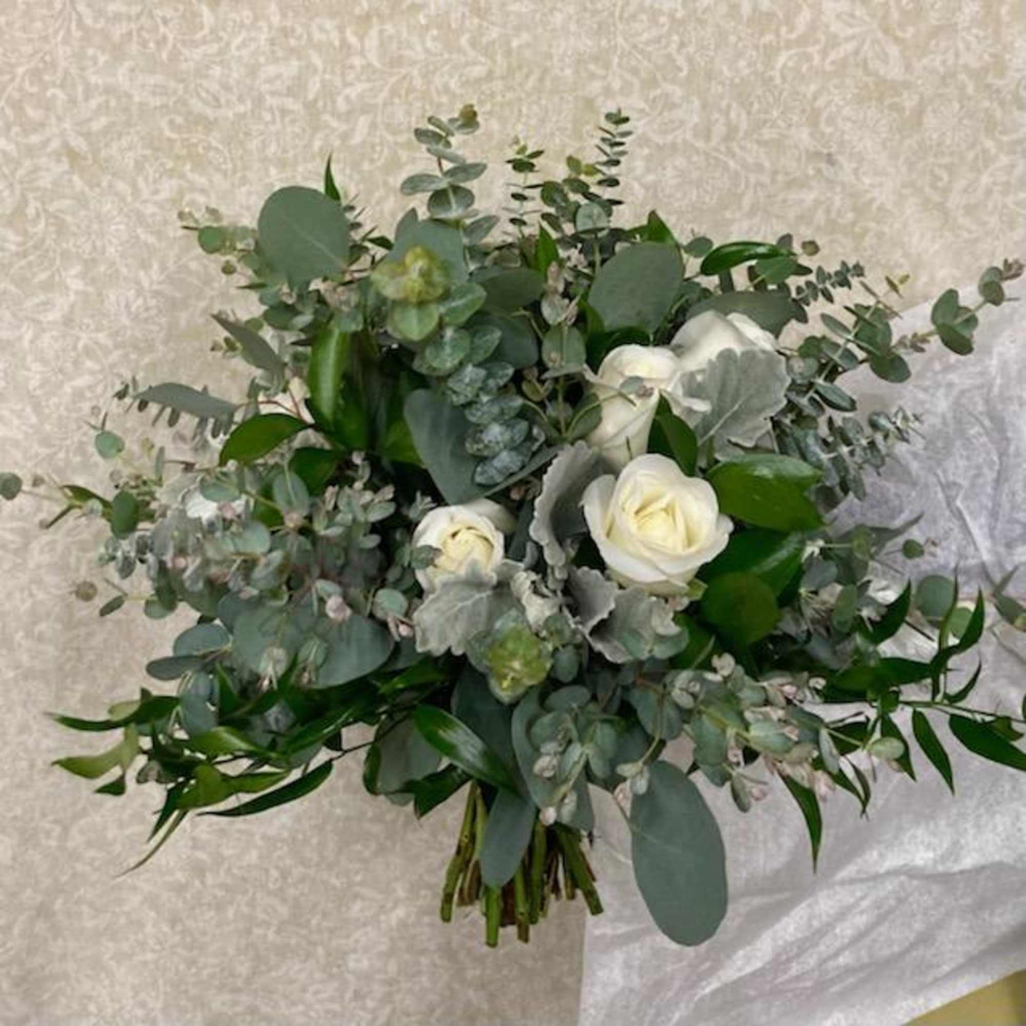White roses and eucalyptus in a loose hand-tied bouquet