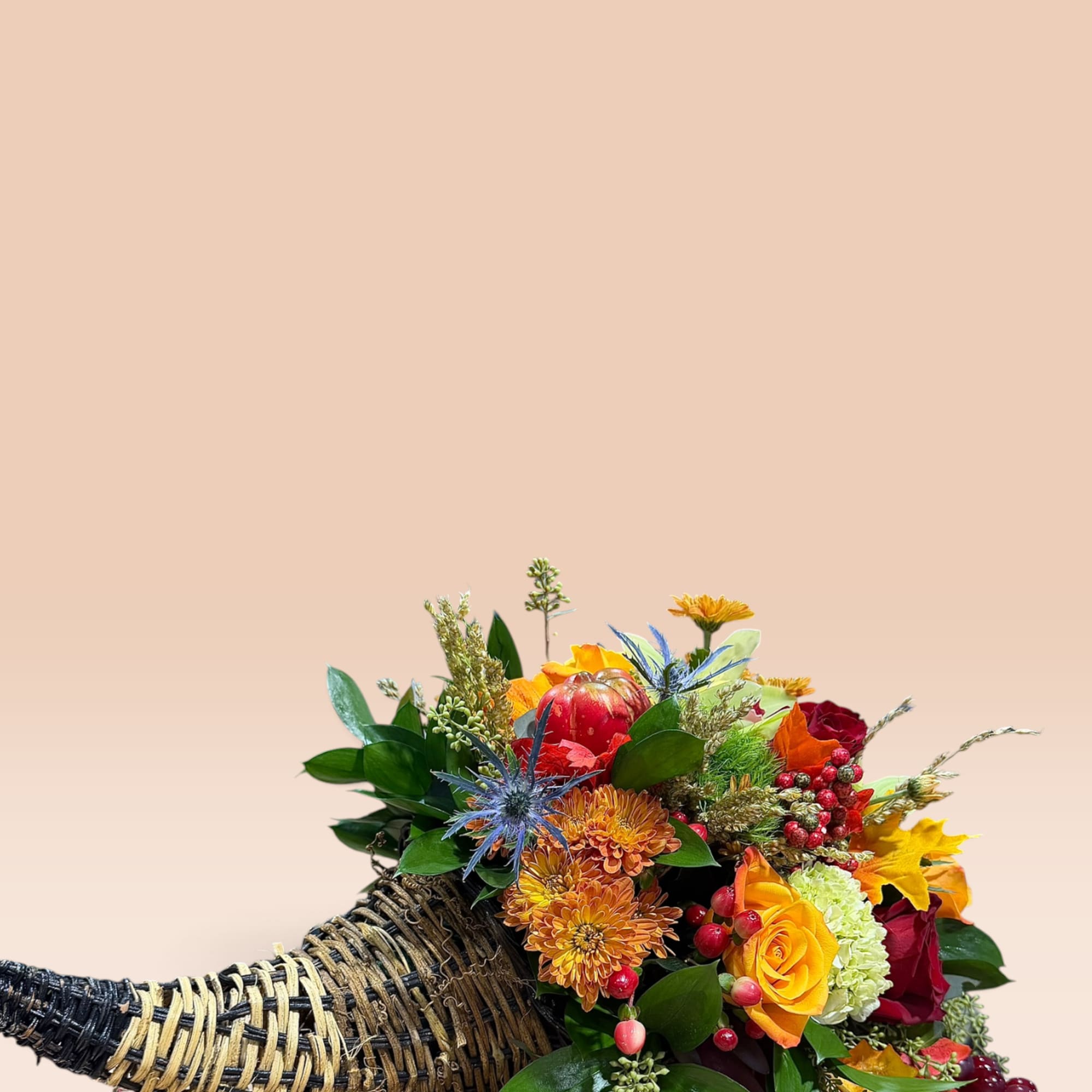 Autumn floral arrangement in a woven cornucopia basket with orange and red blooms