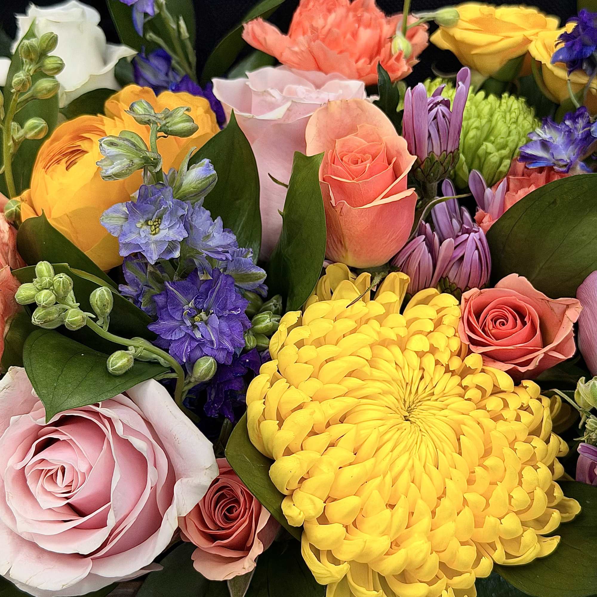 Mixed bouquet of roses, chrysanthemums, and purple flowers in bright colors