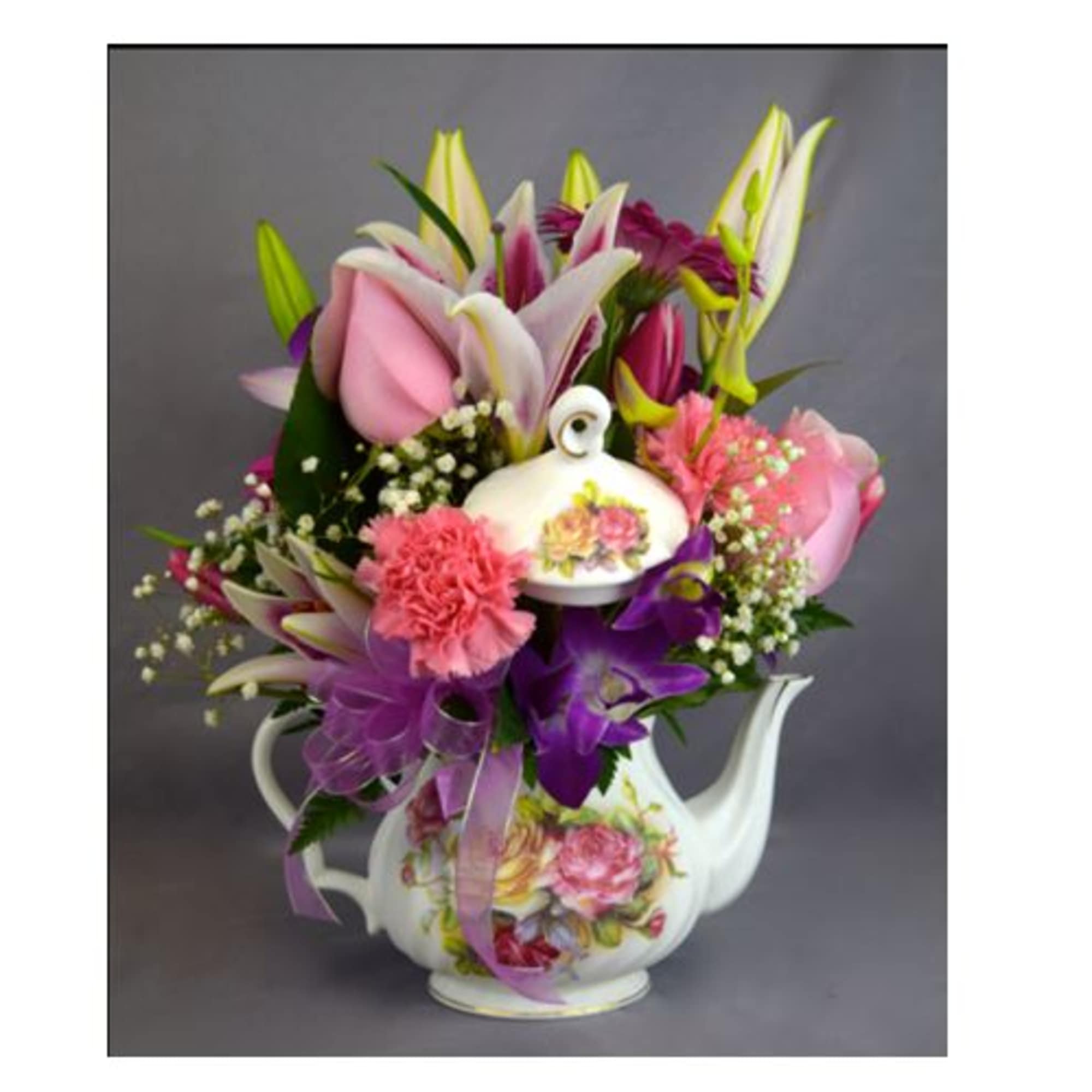 Bouquet of pink and purple flowers in a floral teapot vase
