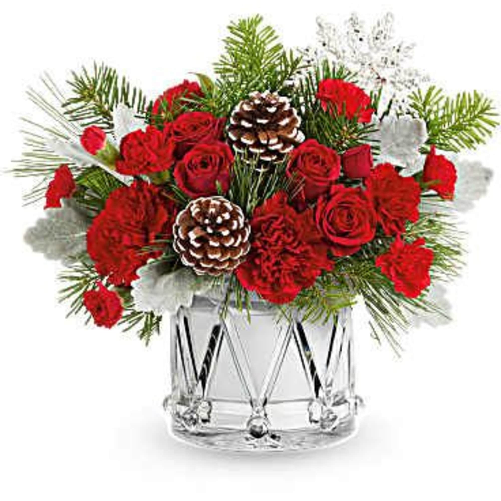 Red roses and carnations in a clear glass vase with pinecones