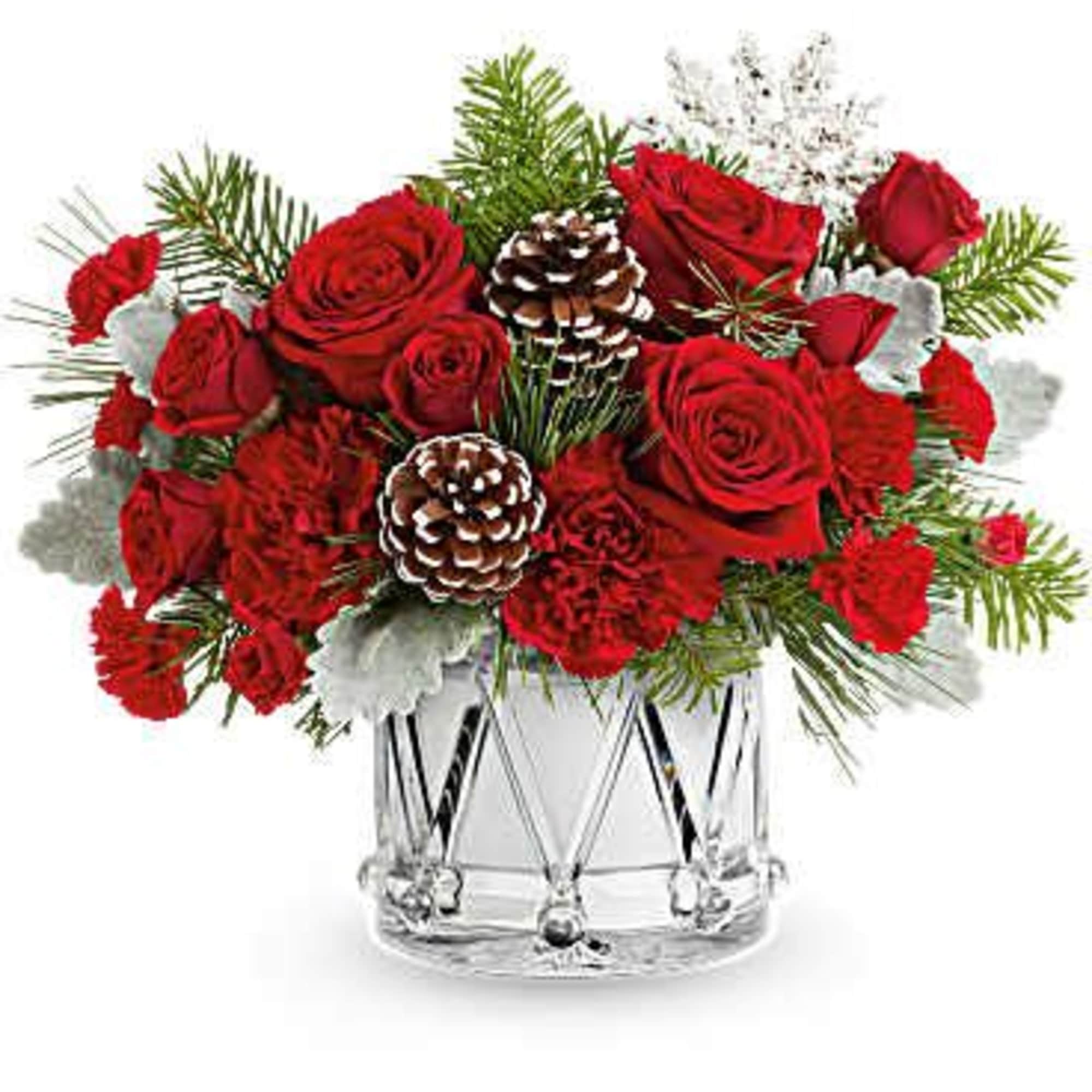 Red roses and carnations in a clear glass vase with pinecones