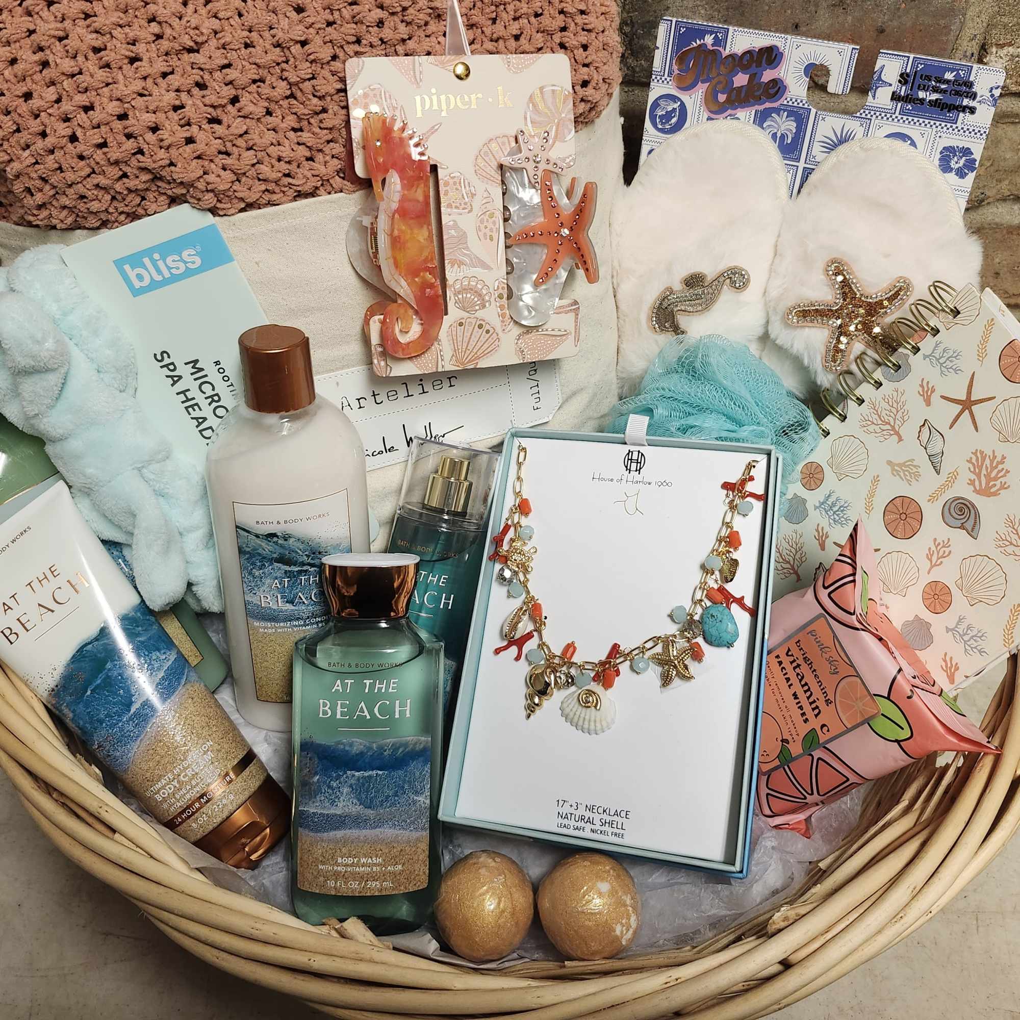 Basket of beach-themed spa gifts with body care, jewelry, and slippers