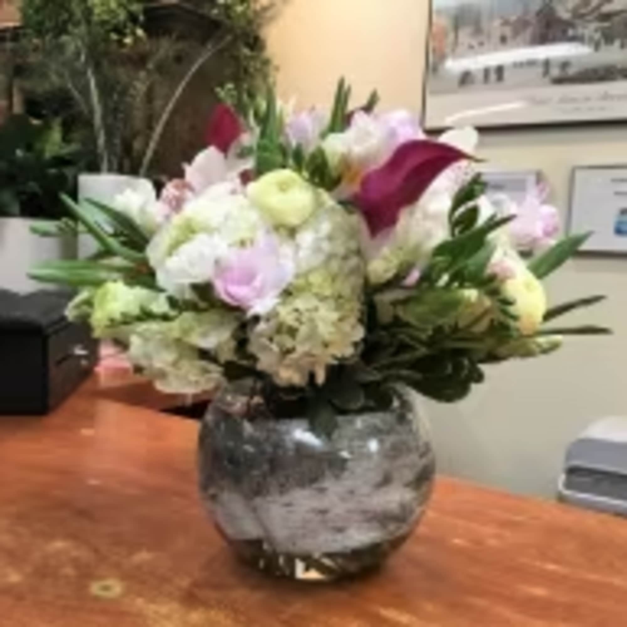Mixed bouquet in a round glass vase with white, pink, and burgundy blooms