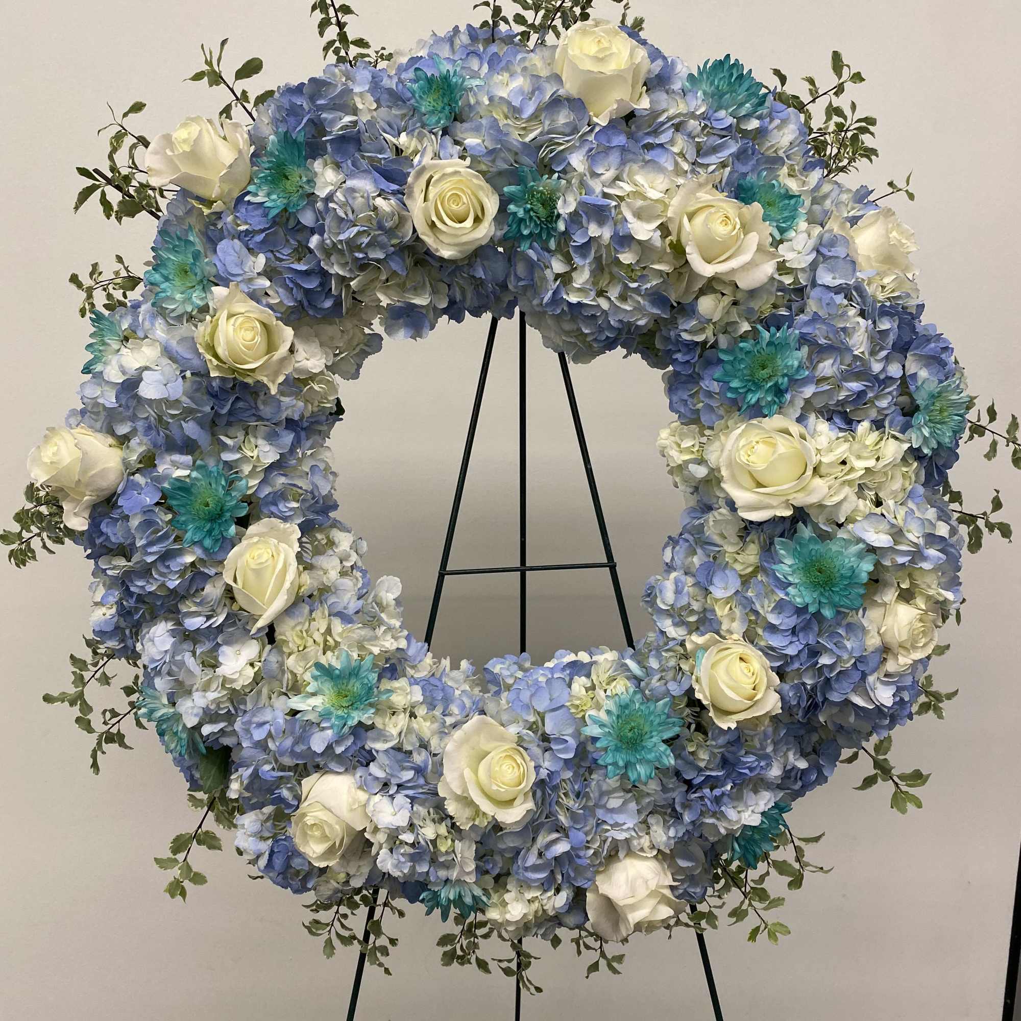 Very large wreath of hydrangeas, roses and greenery. Colors are Light blue