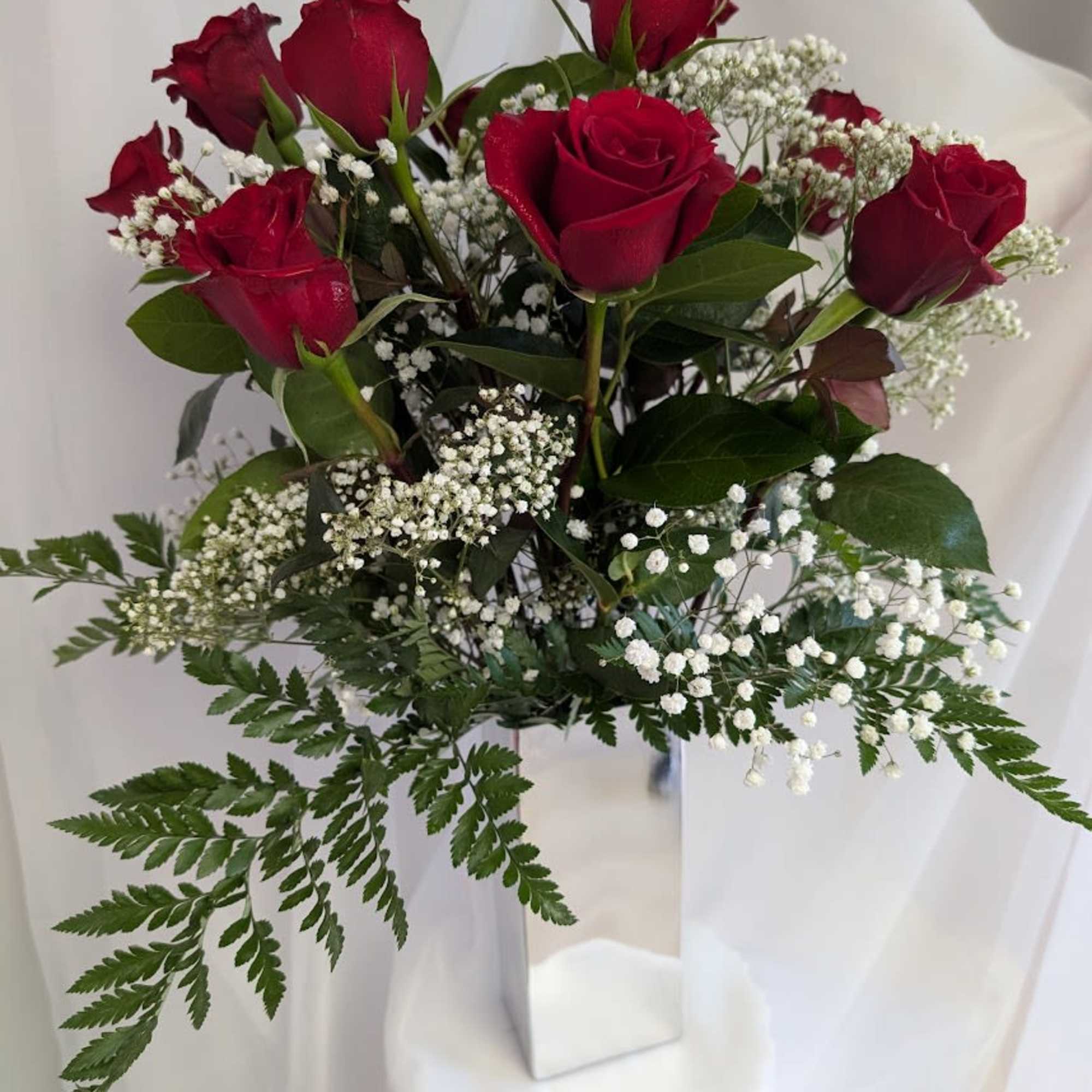 Red roses with baby's breath in a white vase