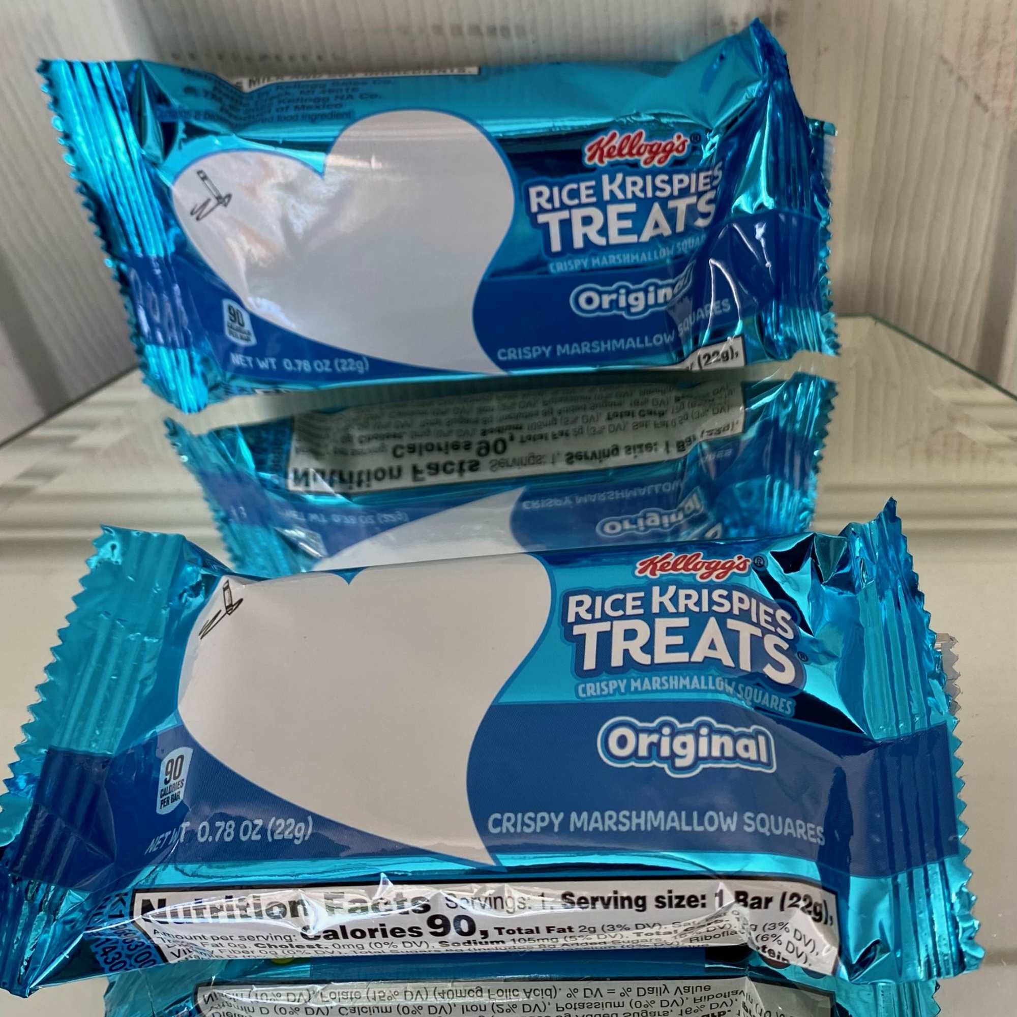Three blue-wrapped Rice Krispies Treats snack bars stacked in a box.