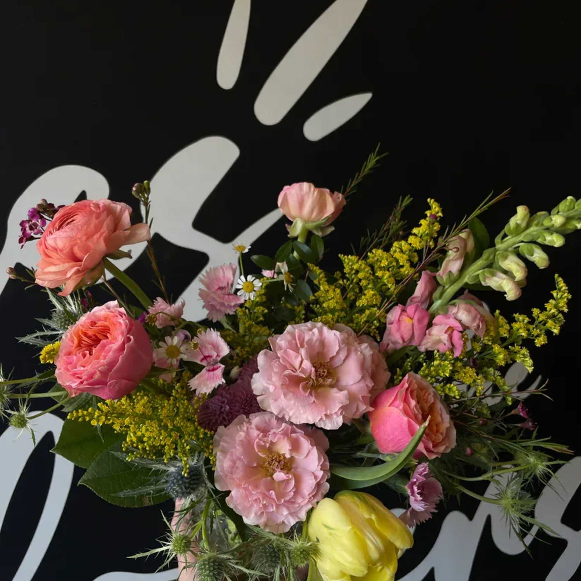 Handheld bouquet of pink, yellow, and white flowers