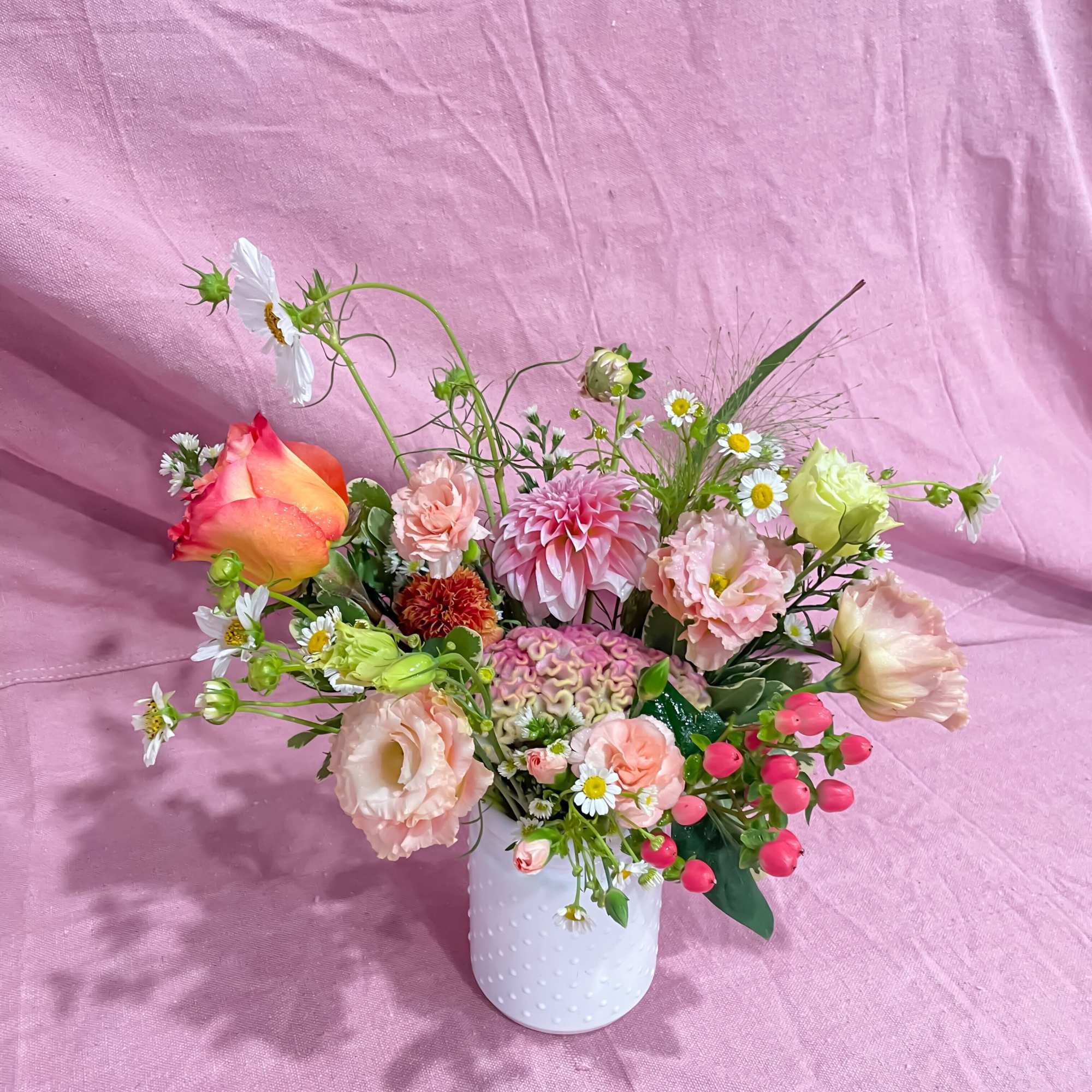 Mixed bouquet in a white textured vase with pink, peach, and white blooms