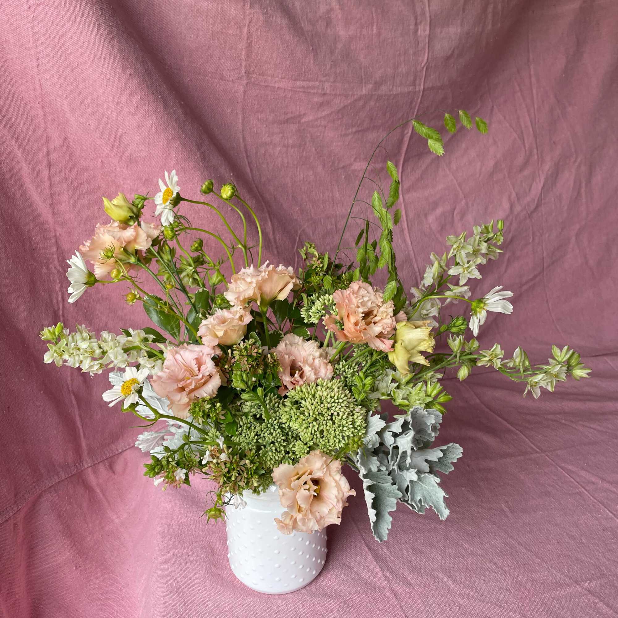 Pastel flower arrangement in a white vase with airy stems and daisies