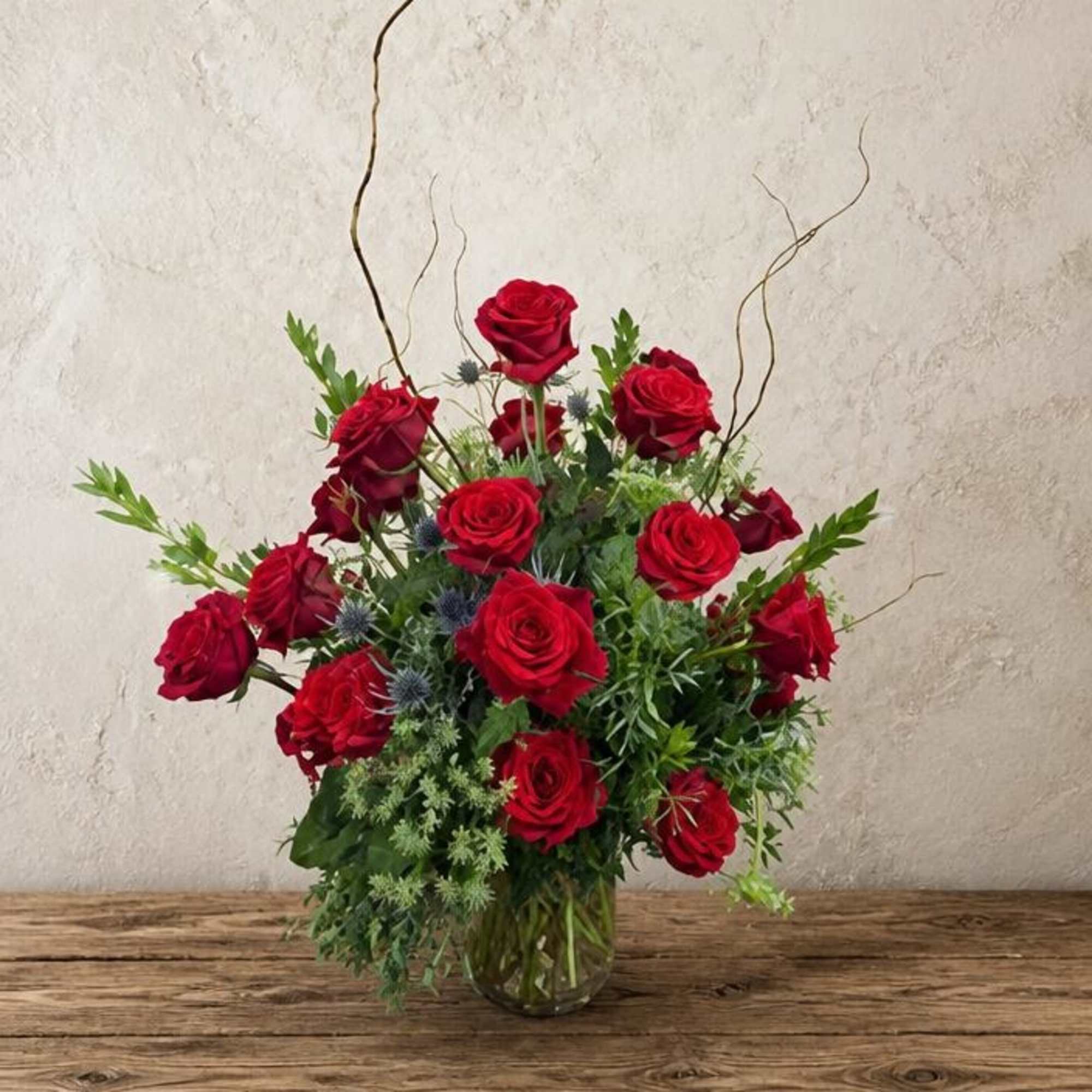 Red roses arranged in a clear glass vase with airy greenery