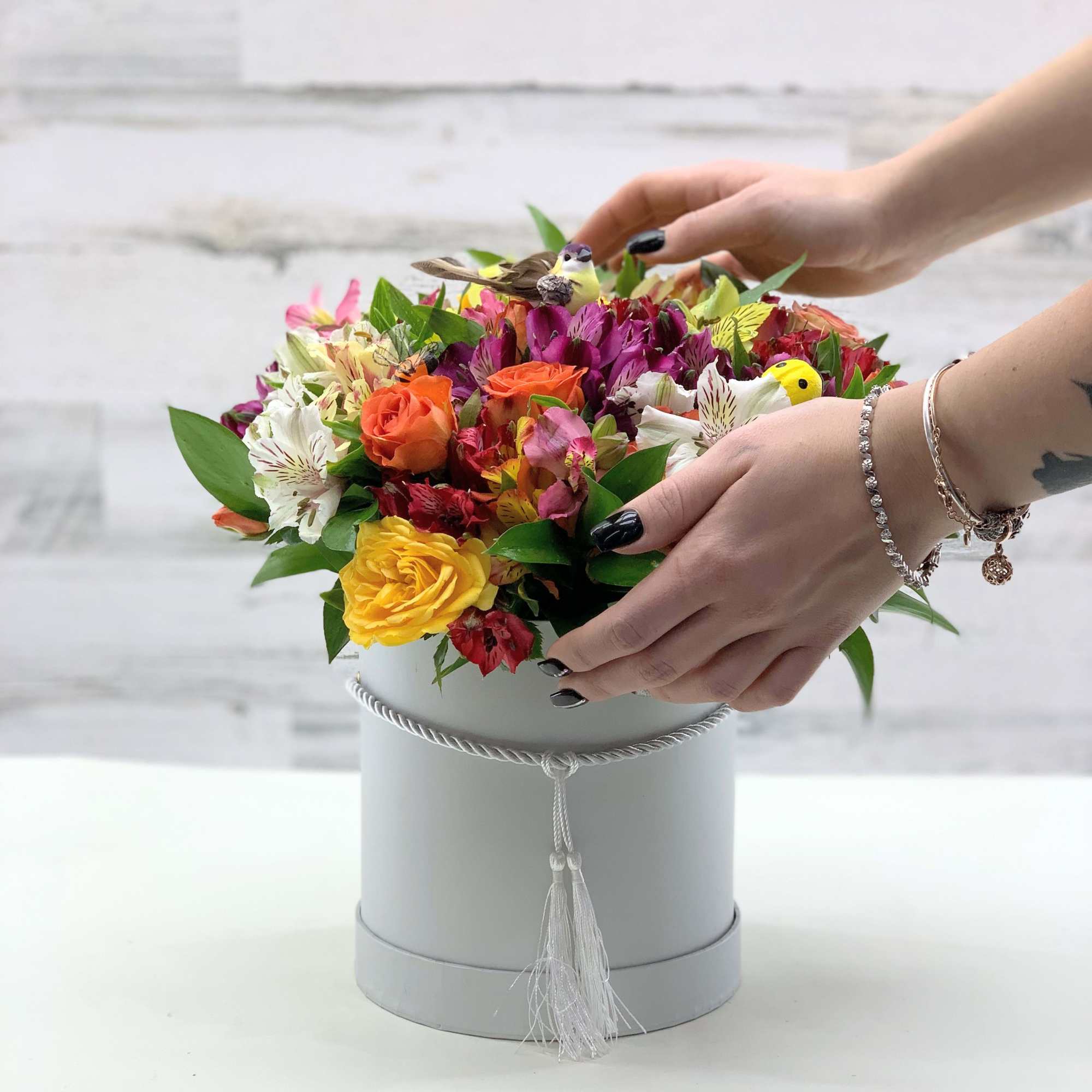 Mixed bouquet in a gray hatbox with bright roses and alstroemeria