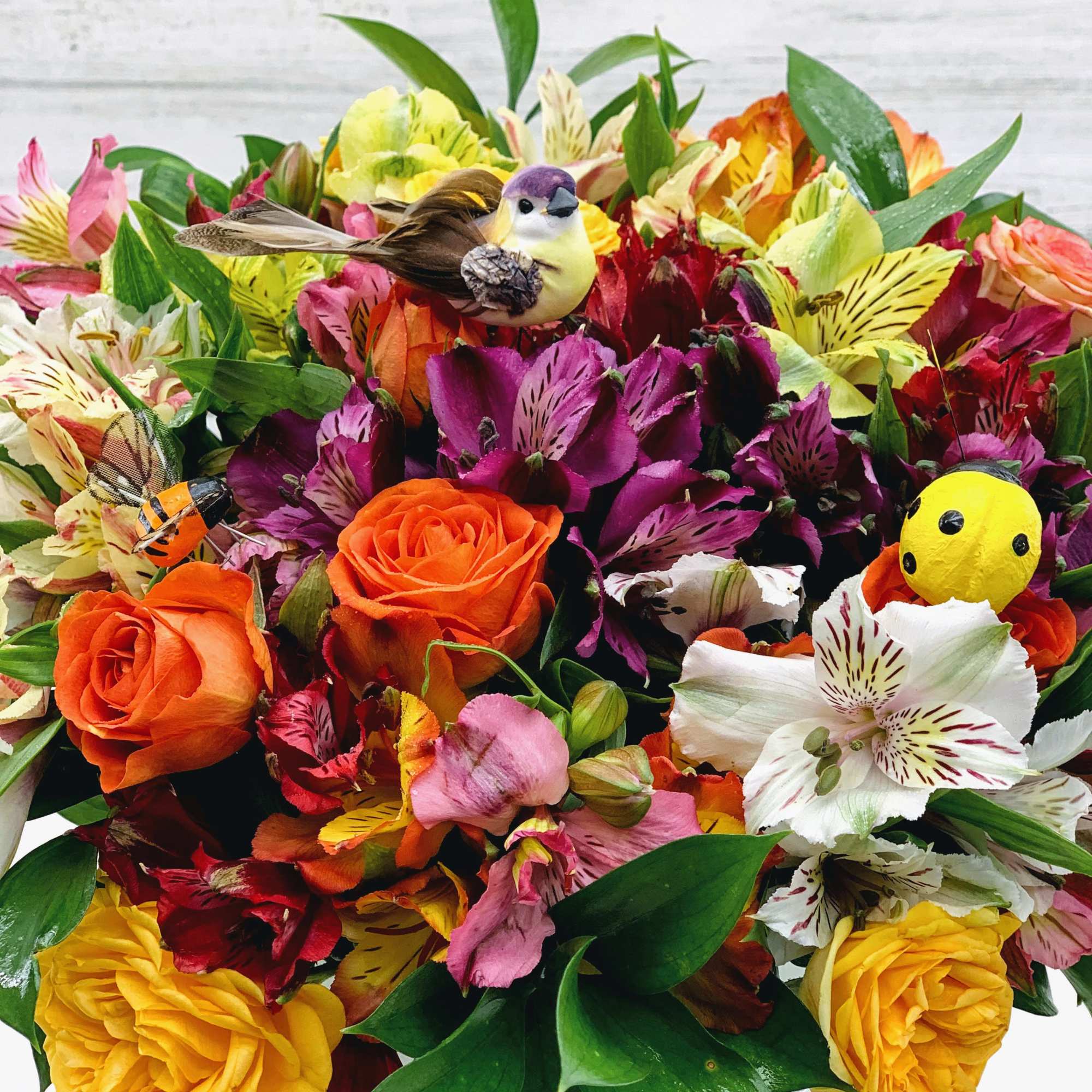 Bright mixed bouquet with roses and alstroemeria in a white container