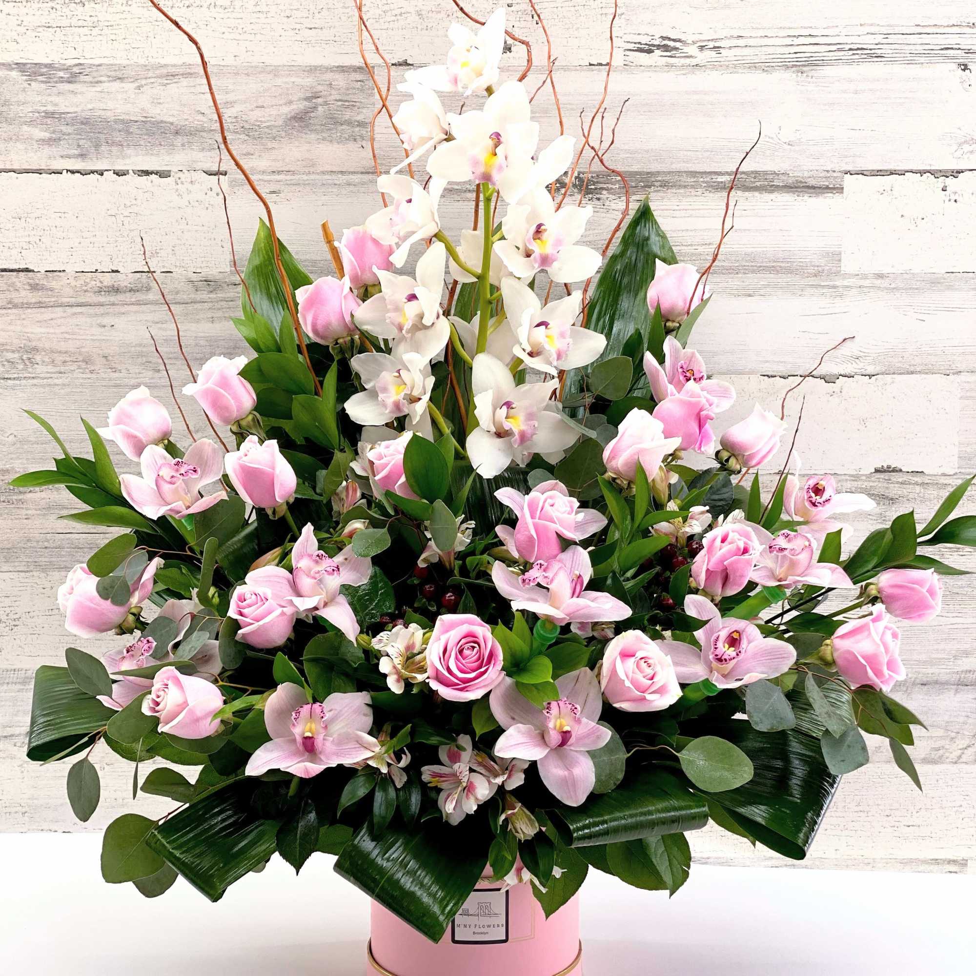 Pink roses and white orchids in a pink hatbox arrangement