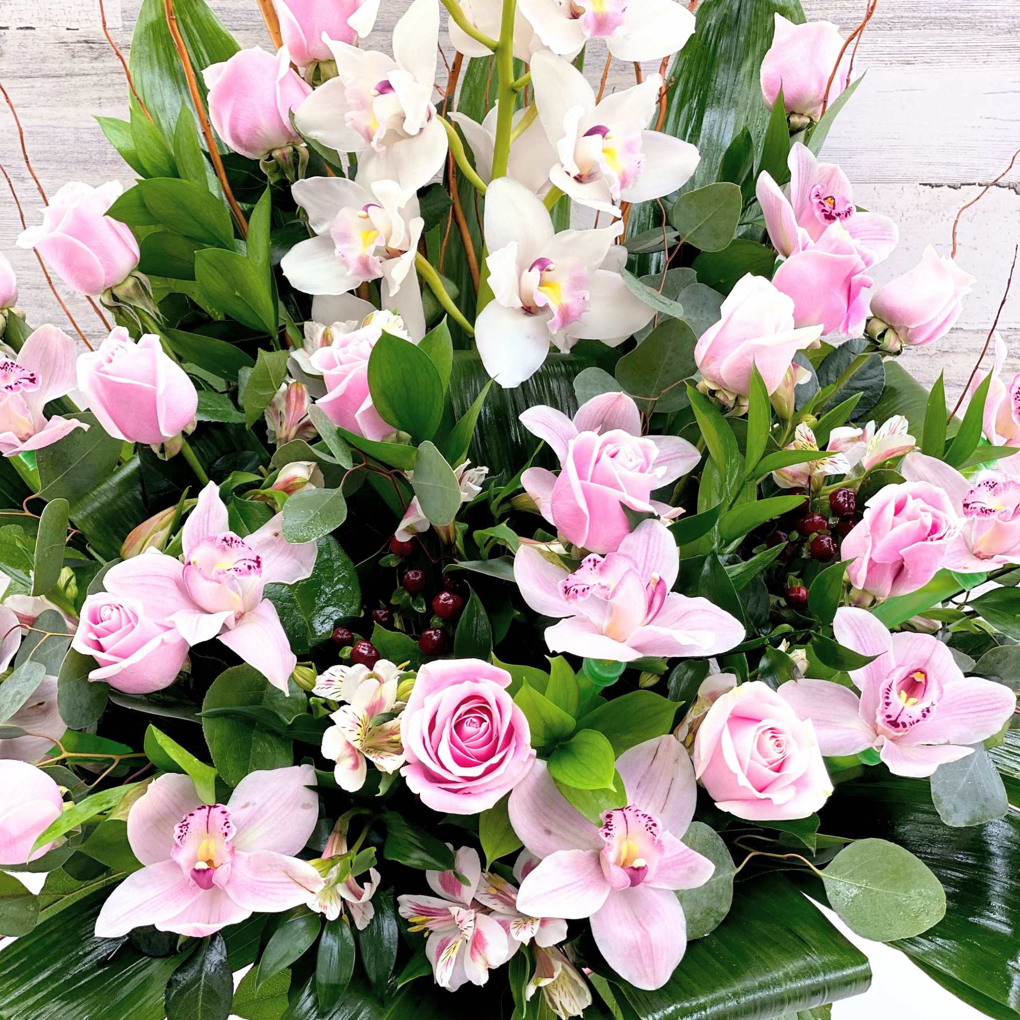 Pink roses and orchids arranged in a low round container