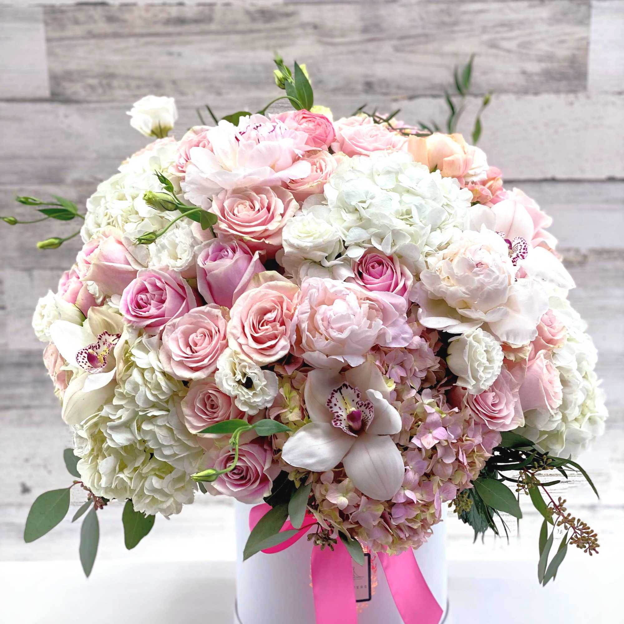 Pink and white rose bouquet in a white hat box with a pink ribbon