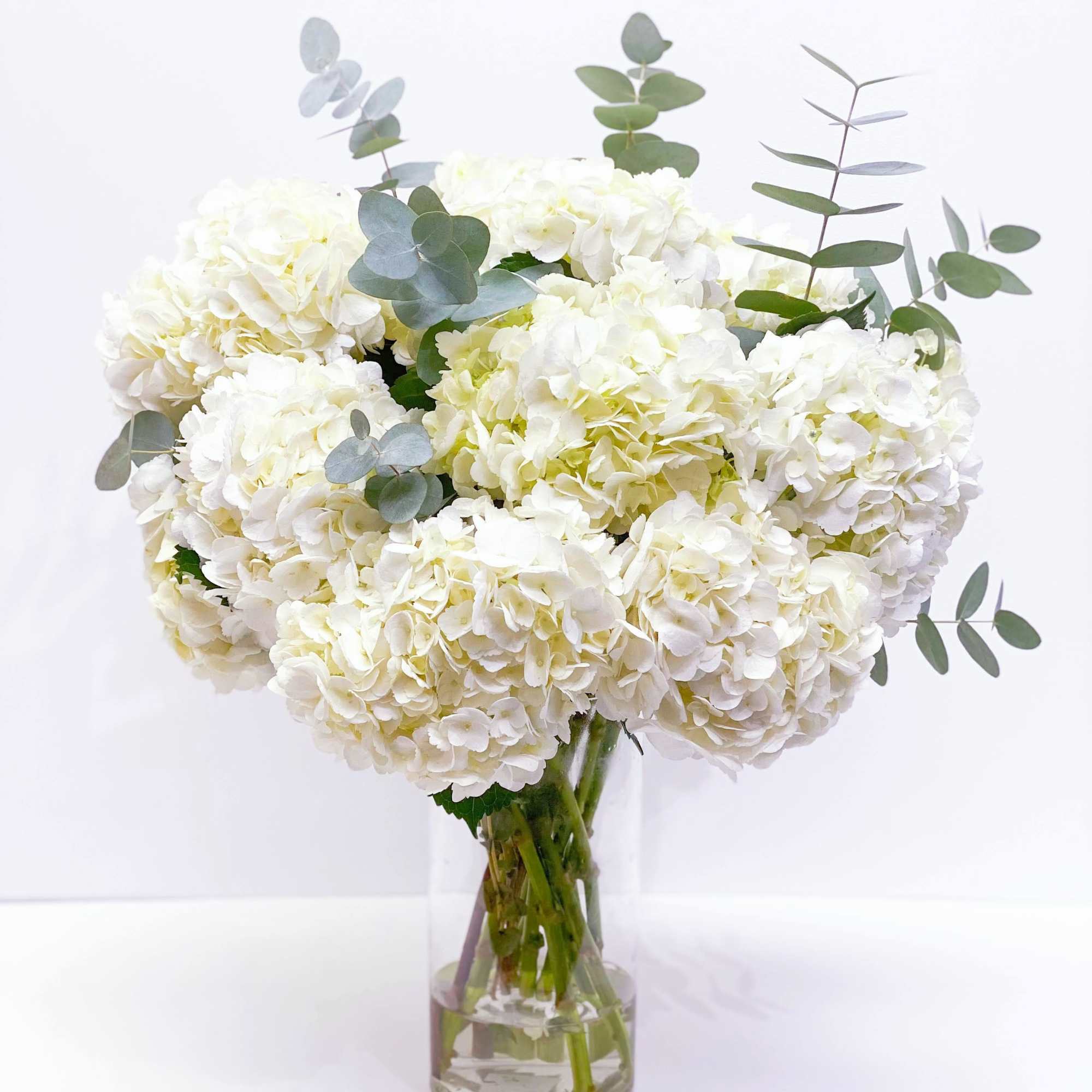 White hydrangea bouquet in a clear glass vase with eucalyptus