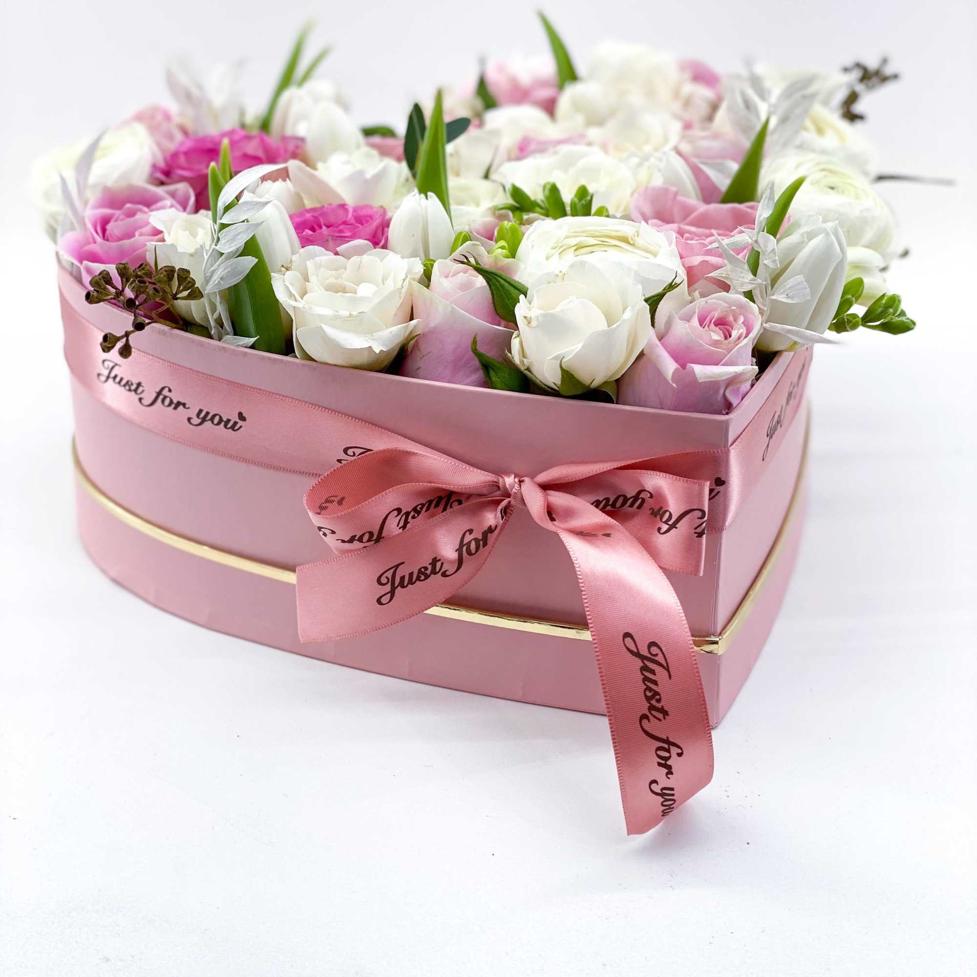Pink and white roses in a pink heart-shaped box with a ribbon