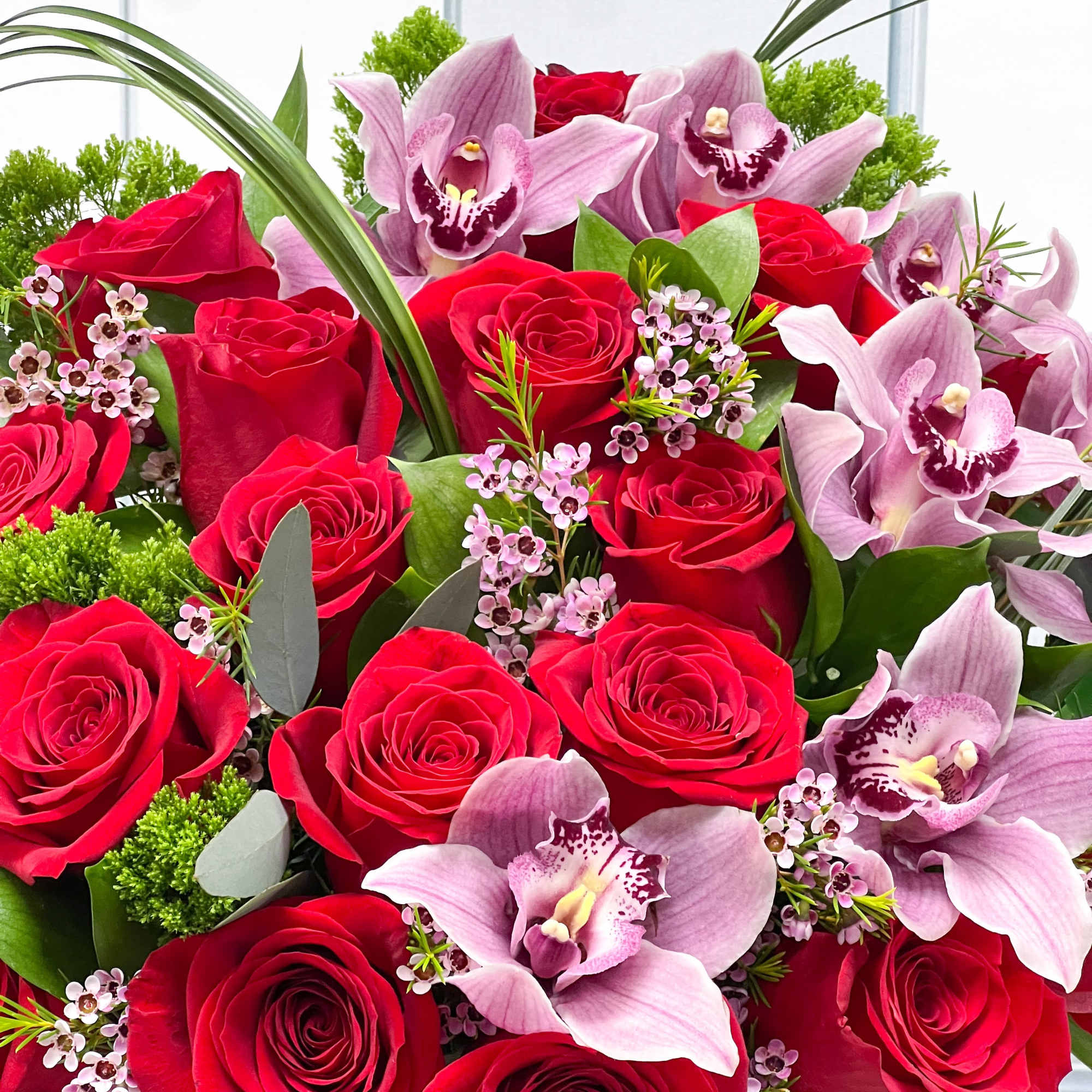 Red roses and pink orchids in a black vase