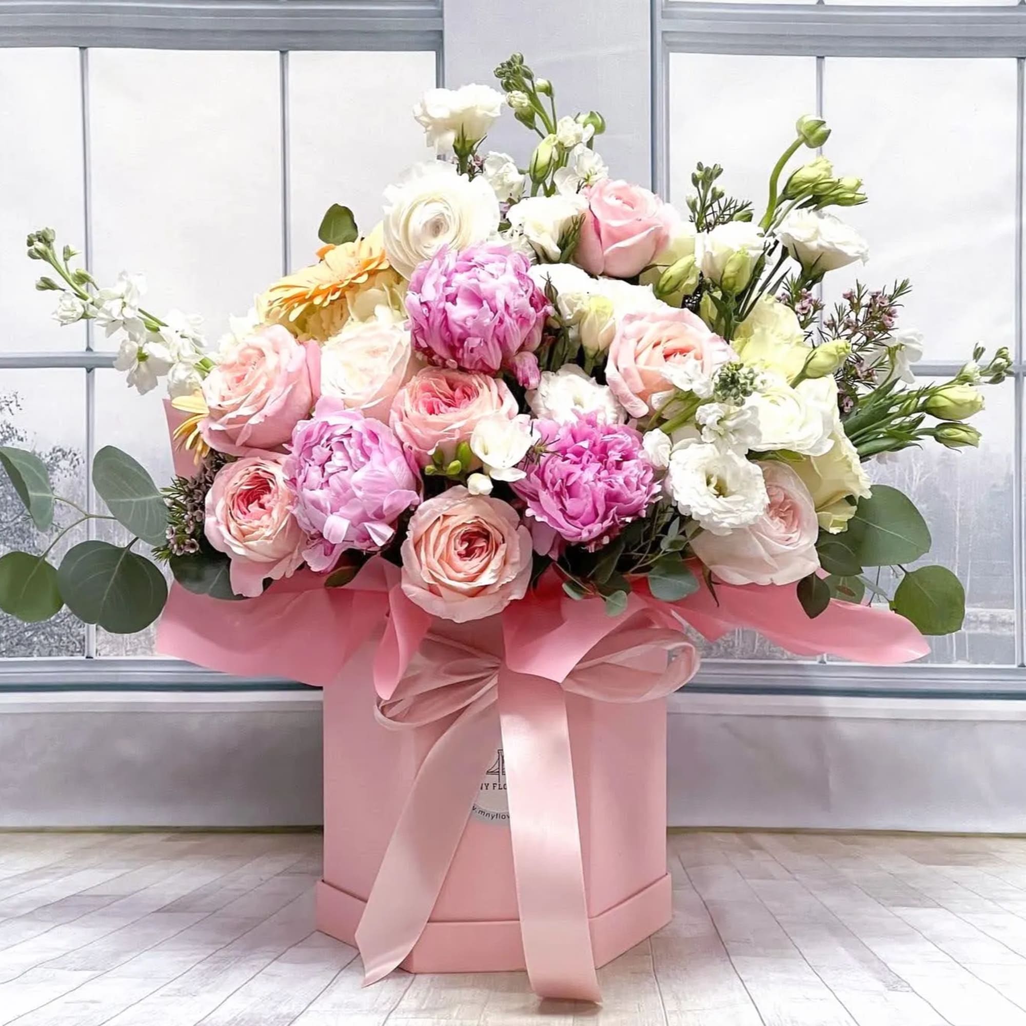 Pink and white roses in a pink hat box with a ribbon