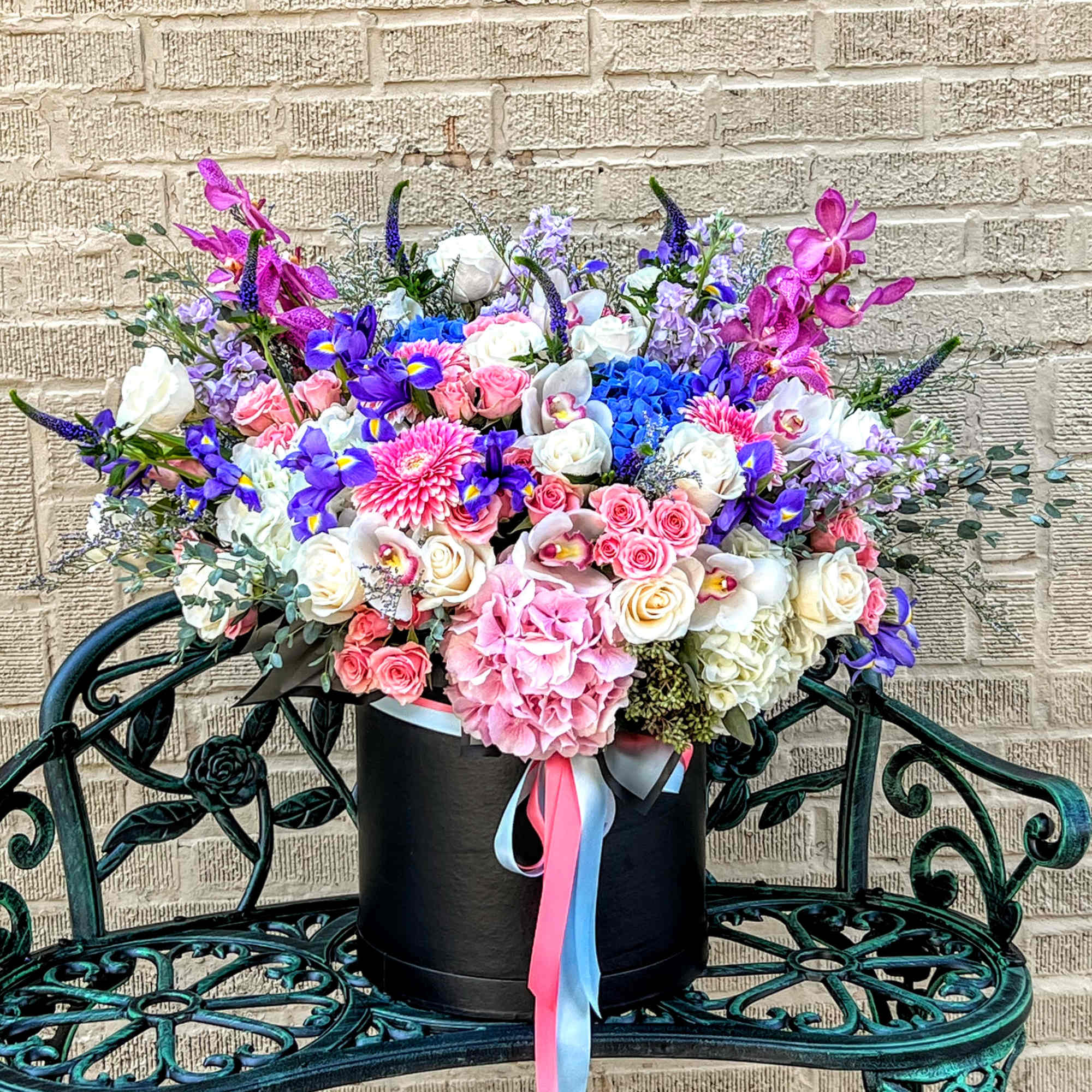 Colorful mixed bouquet in a black hatbox with pink and blue ribbons