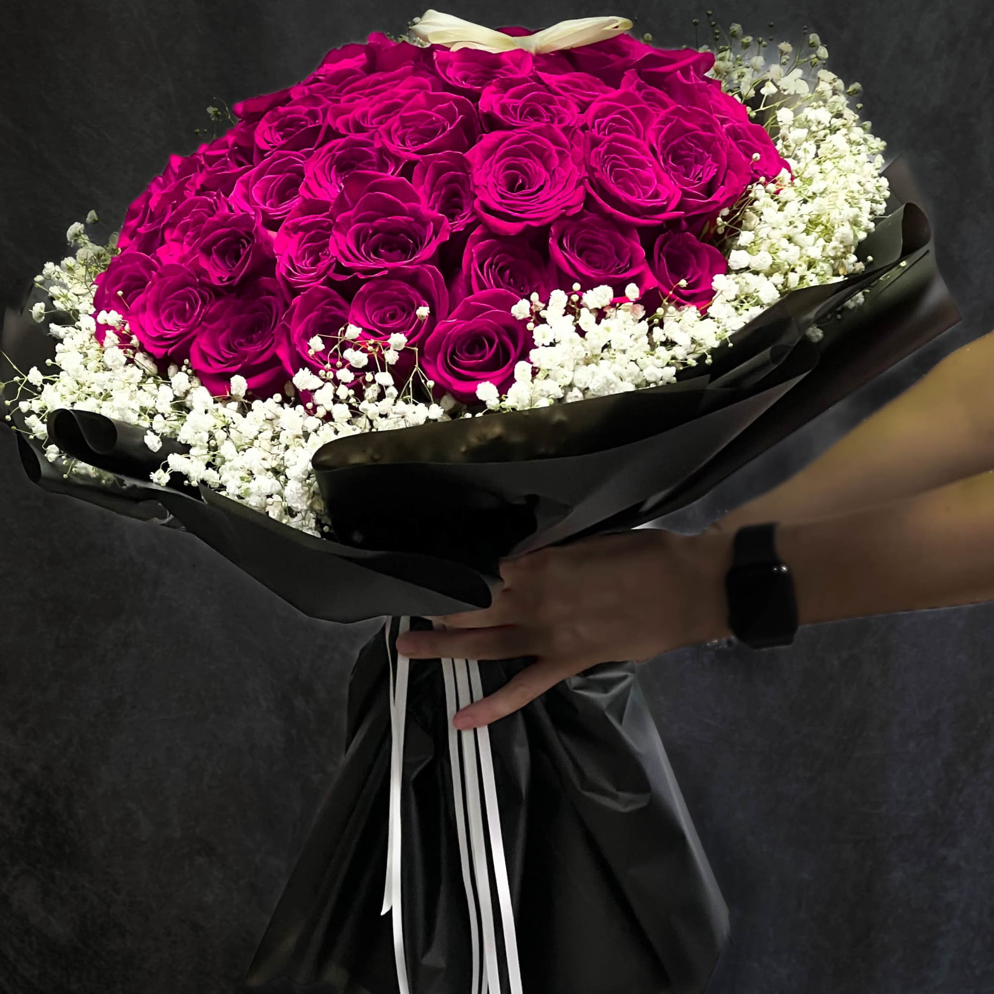 Bouquet of hot pink roses with white baby's breath in black wrapping